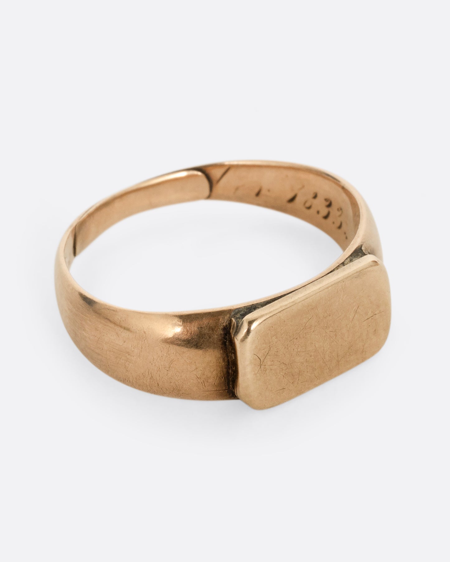 A yellow gold signet ring with a rectangular face. Shown from the side.
