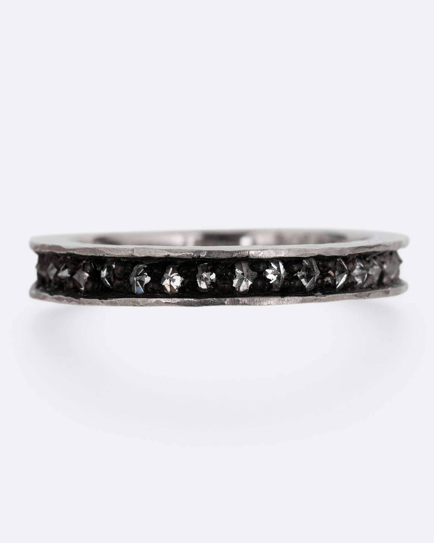 A palladium ring with a queue of diamonds set in a darkened center channel. Shown from the front.