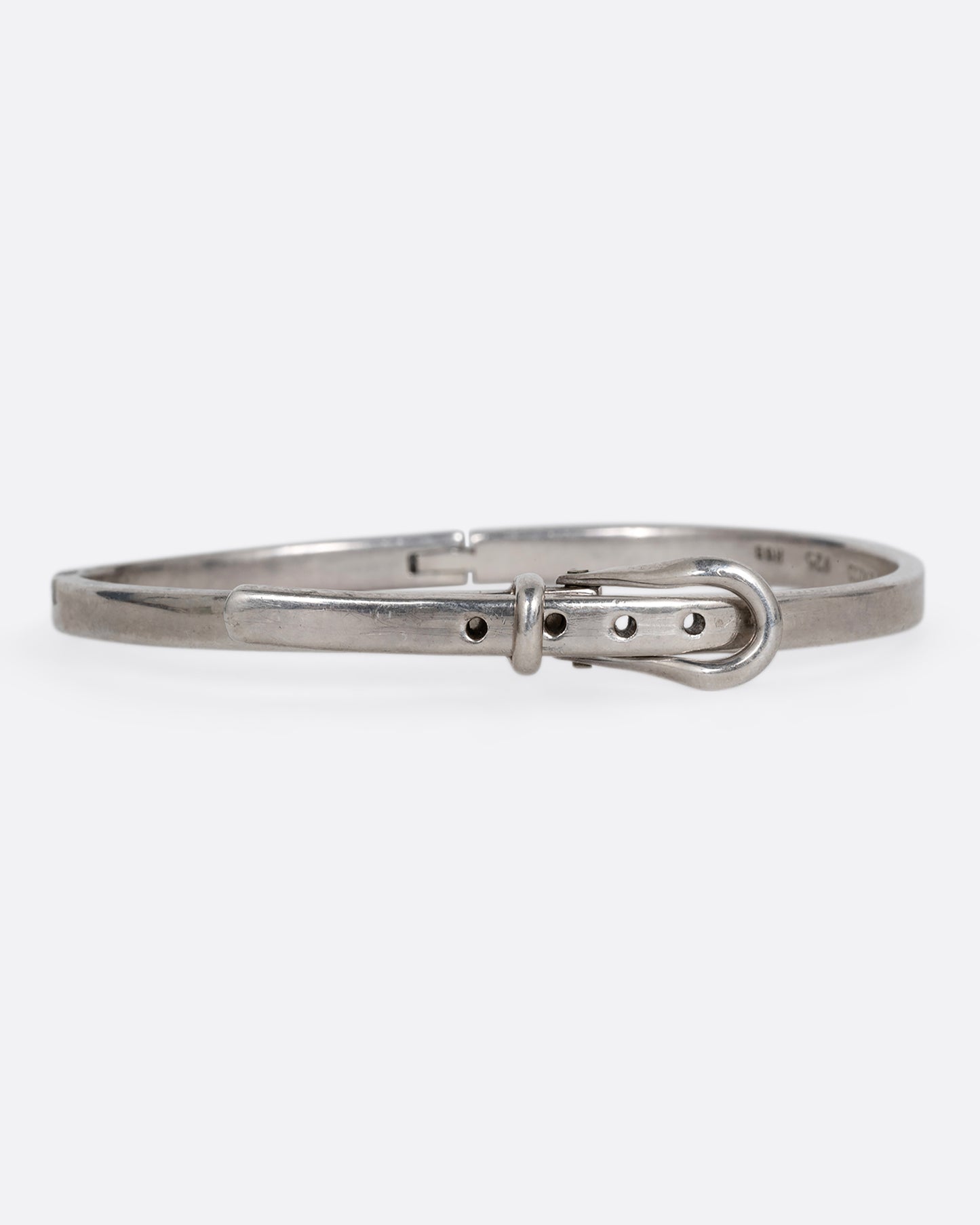 A narrow silver hinged bracelet with a buckle front. Shown from the front.
