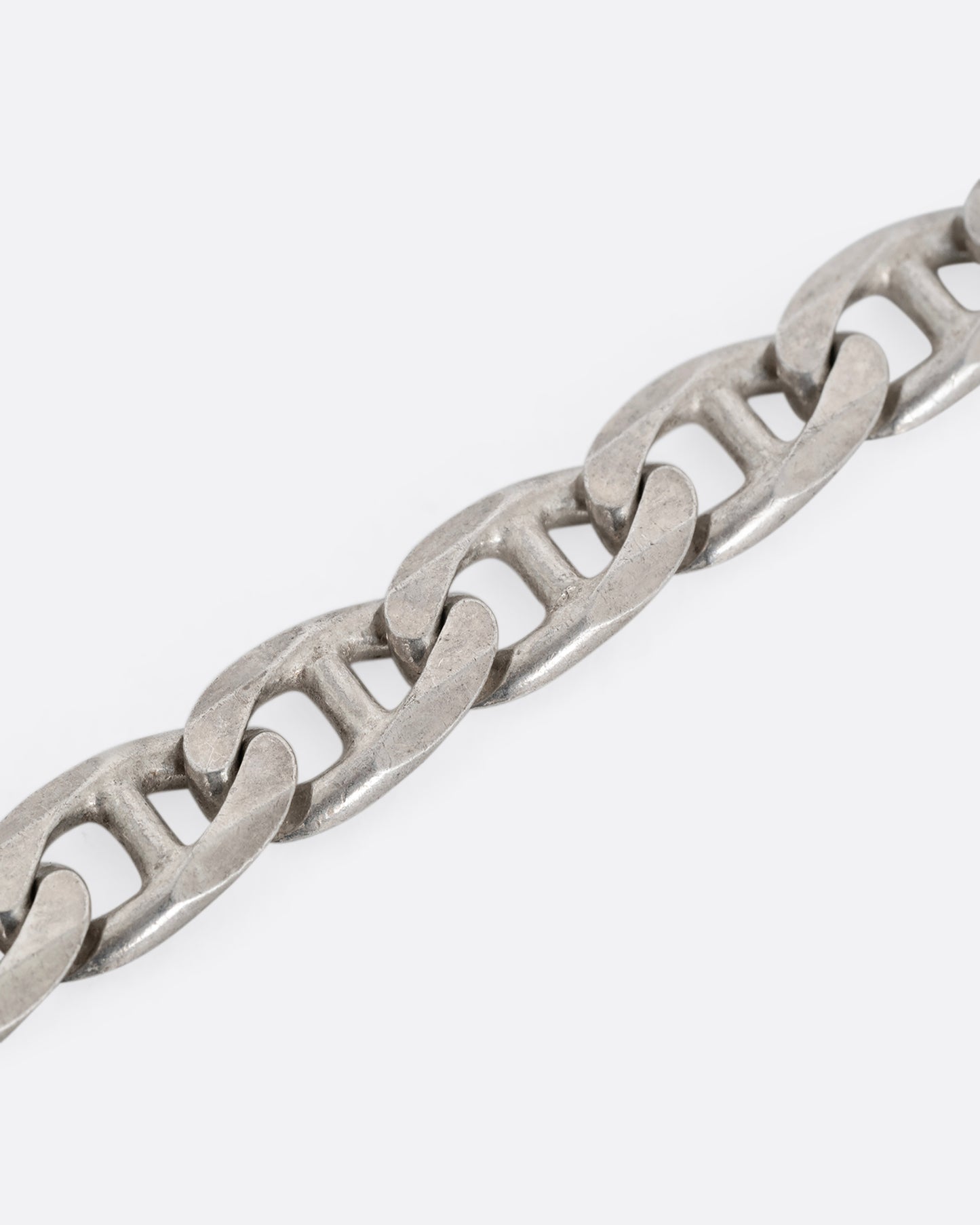 A close up of a silver anchor link chain necklace, shown from the front.