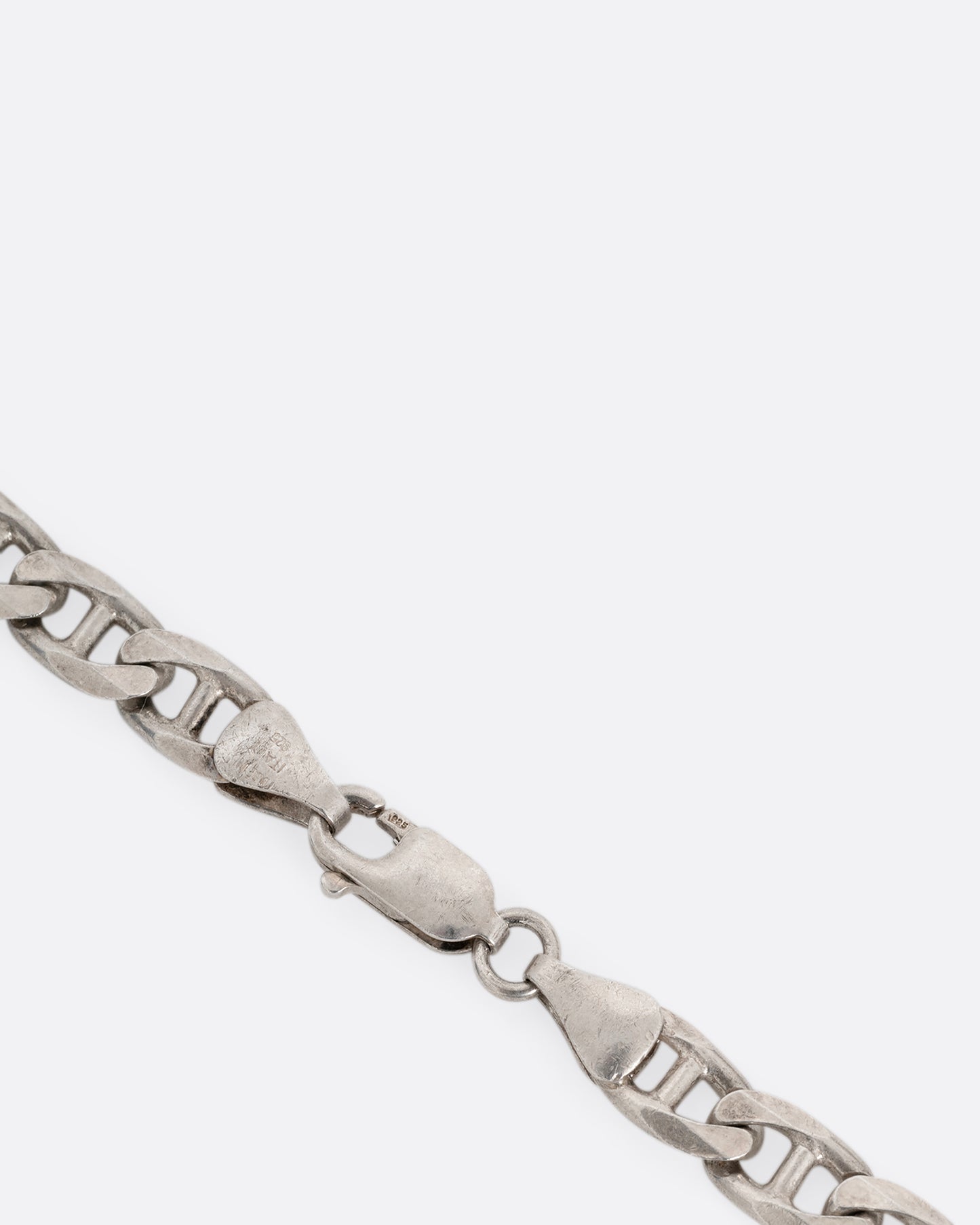 A close up of the clasp of a silver anchor link chain necklace, shown from the front.