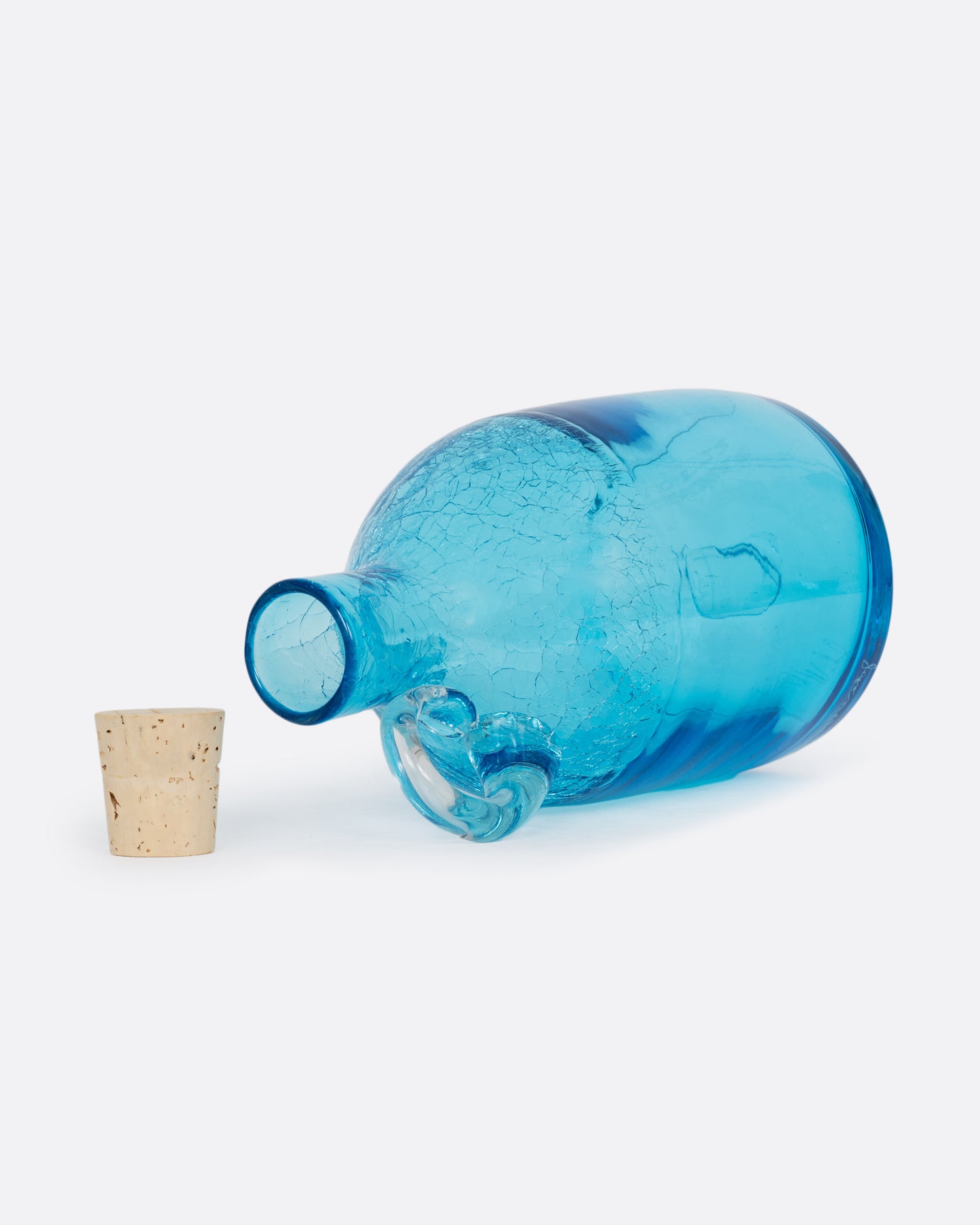 A glass aqua moonshine jug from Blenko with a clear crystal handle, a crackled finish at the top, and a cork stopper. Shown lying flat open at an angle from the top.