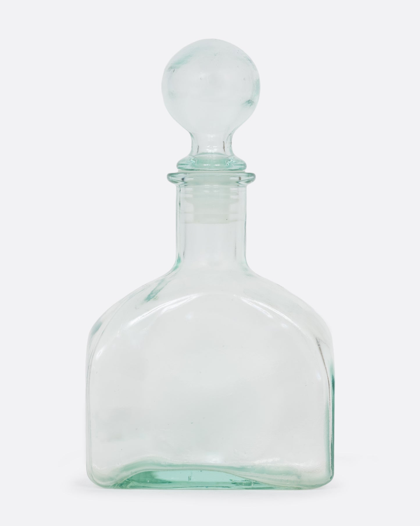 A clear glass decanter with a sphere shaped top. Shown from the front.