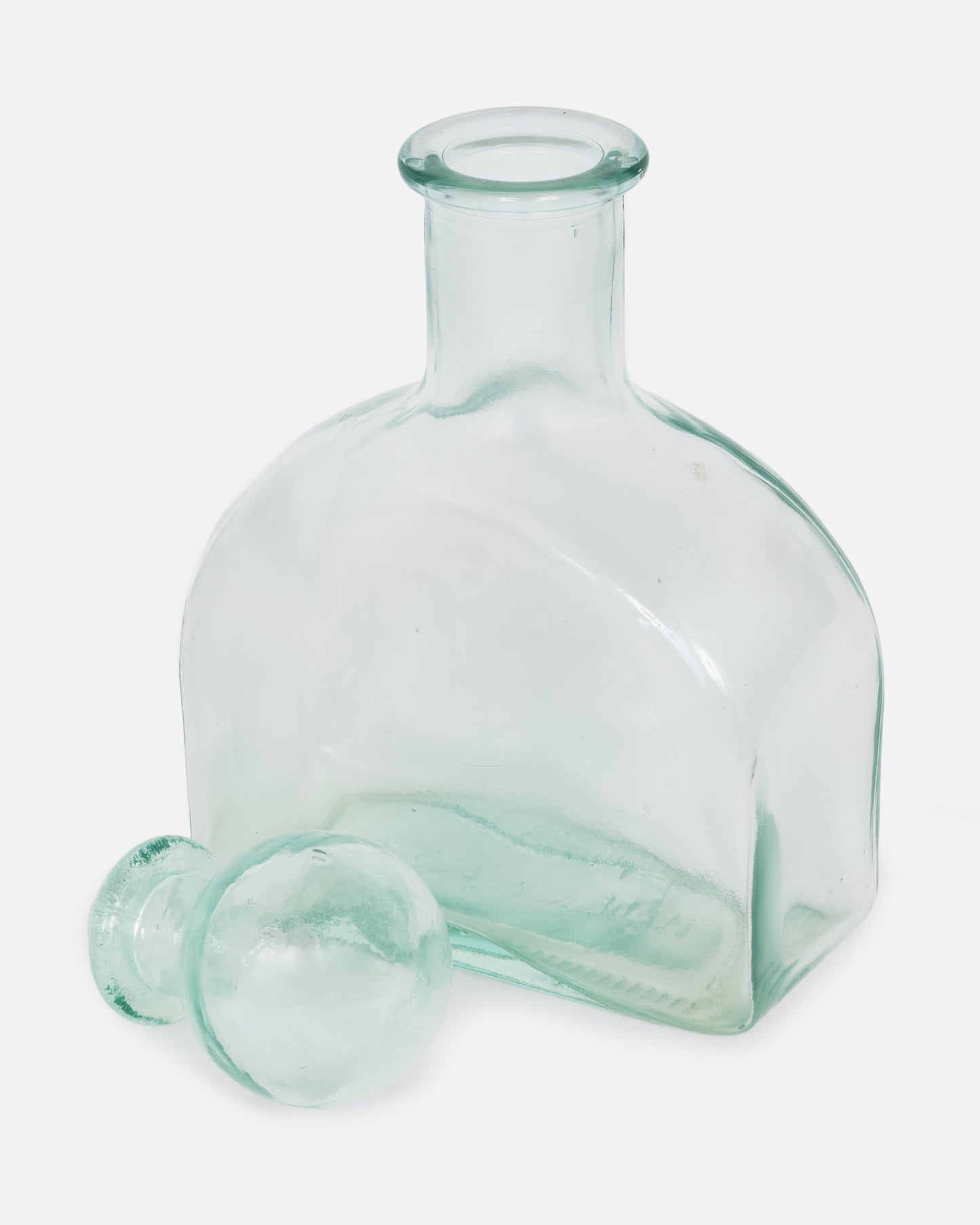 A clear glass decanter with a sphere shaped top. Shown open at an angle from the front.