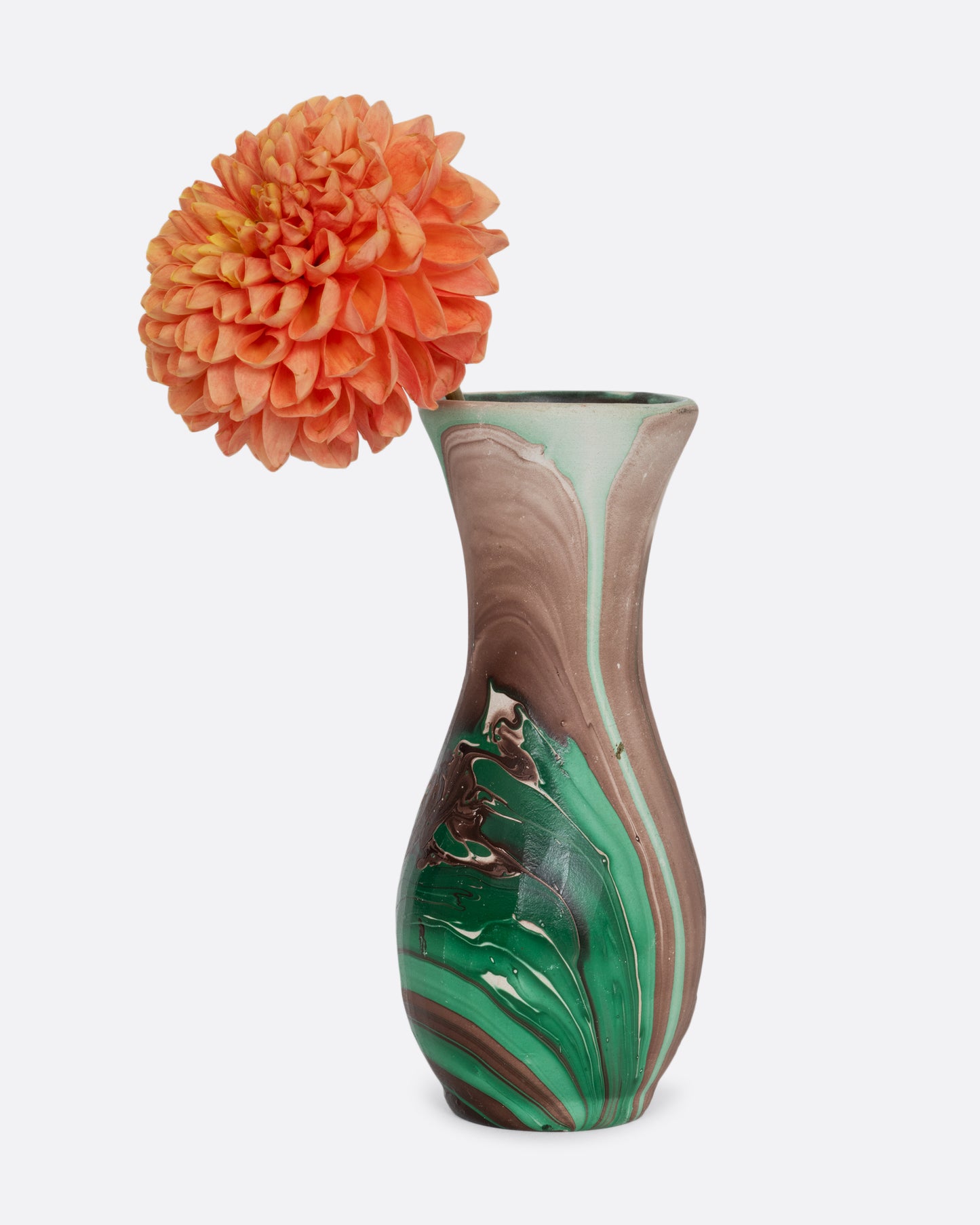 A green and brown swirled vase with an orange flower in it. Shown from the front.