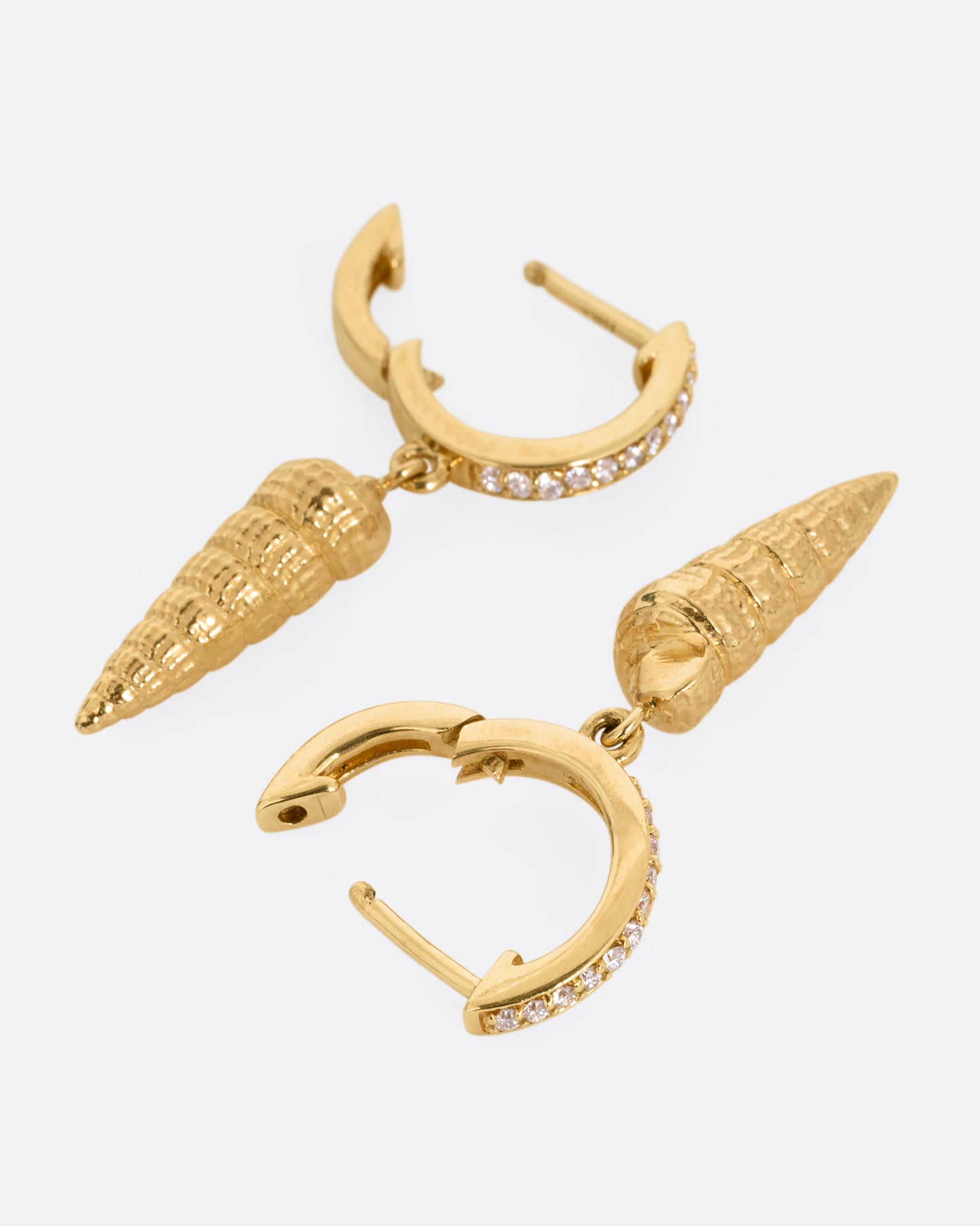 A pair of yellow gold diamond lined hoop earrings with seashell drops. Shown open from the front.
