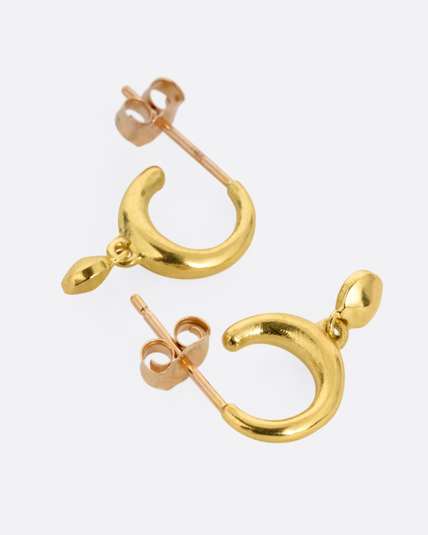 A pair of yellow gold huggie hoop earrings with gold bead dangles. One earring I shown from the front, the other from the back.