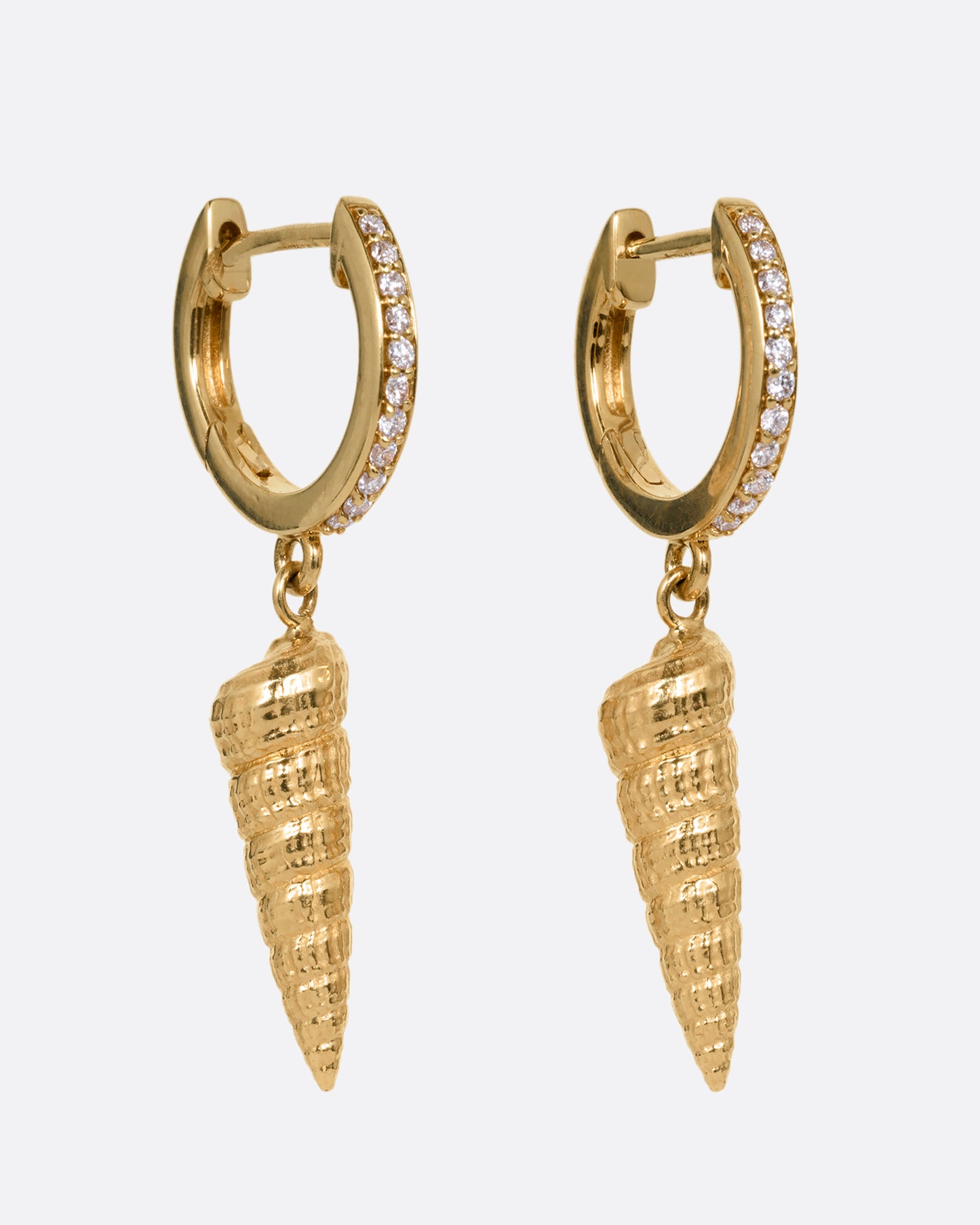 A pair of yellow gold diamond lined hoop earrings with seashell drops. Shown from the side.