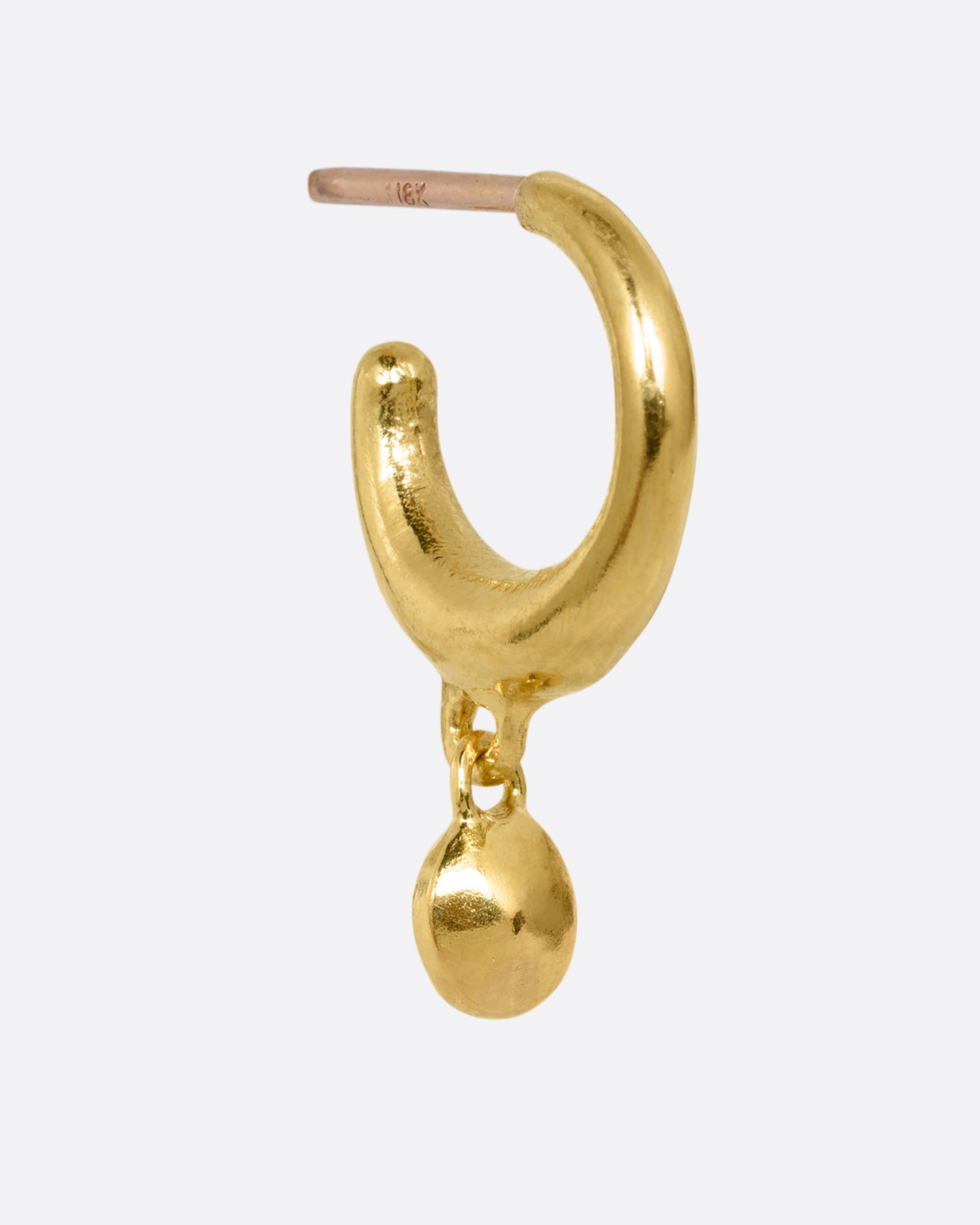 A yellow gold huggie hoop earring with a gold bead dangle. Shown from the side.