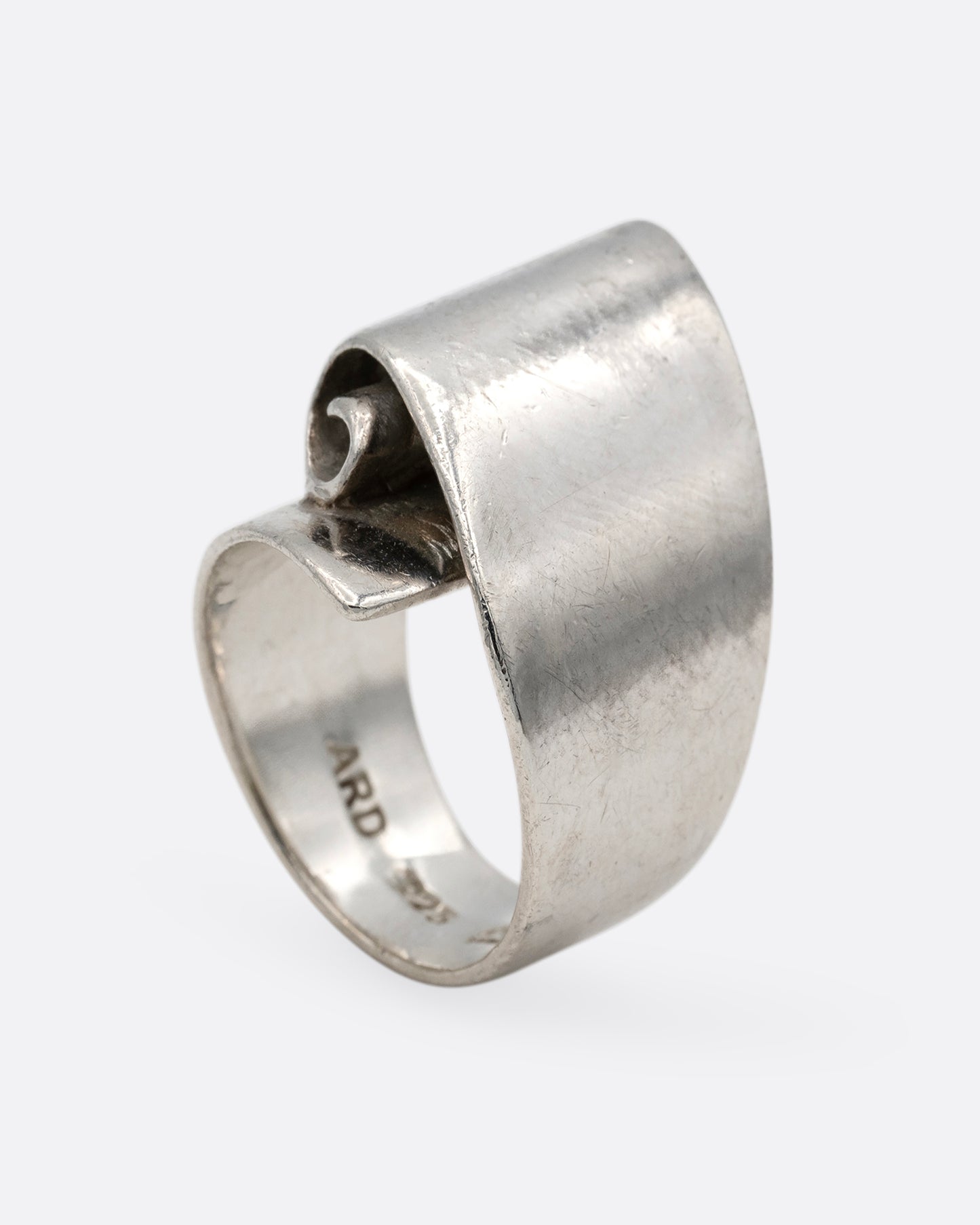 A silver ring with a scroll on its face. Shown from the bottom.