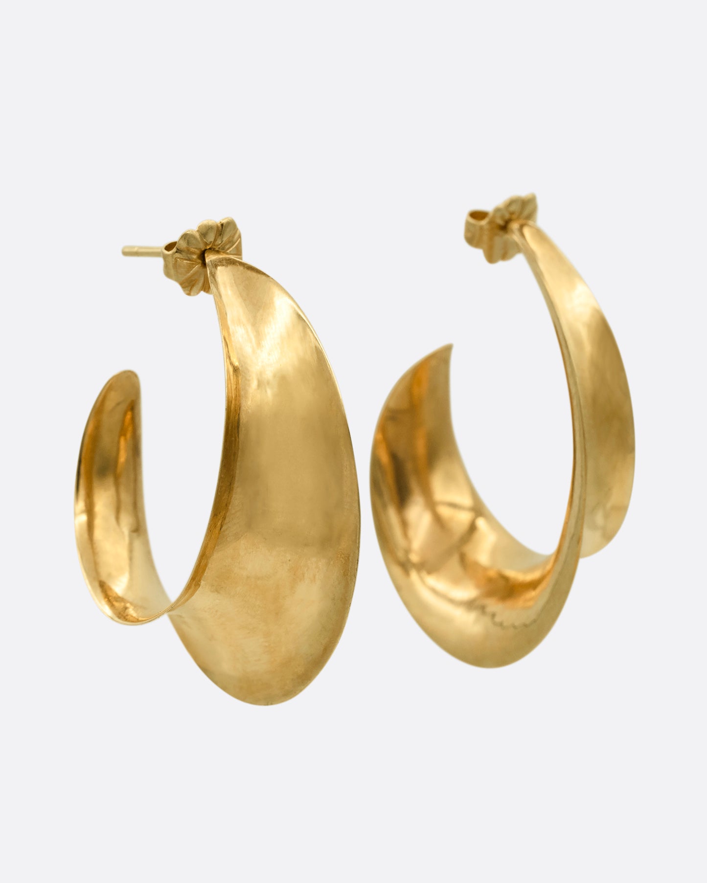 Yellow gold hoop earrings with a ribbon- like shape. Shown from the side.