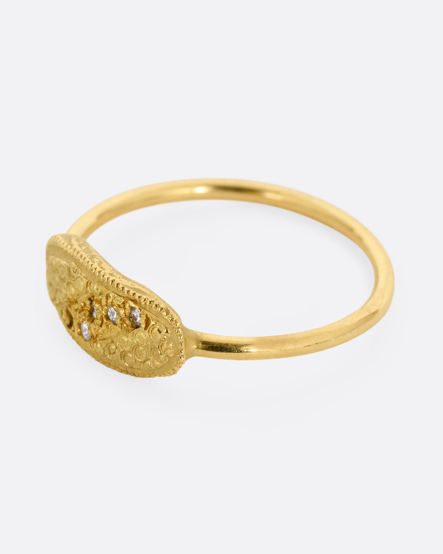 A yellow gold ring with a textural finish and five diamonds. Shown from the side.
