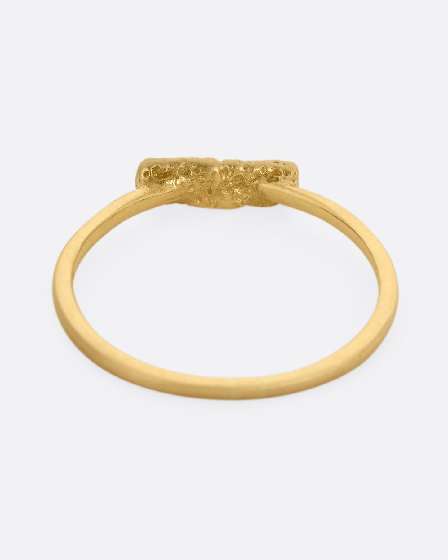 A yellow gold ring with five diamonds set on a textured face. Shown from the back.