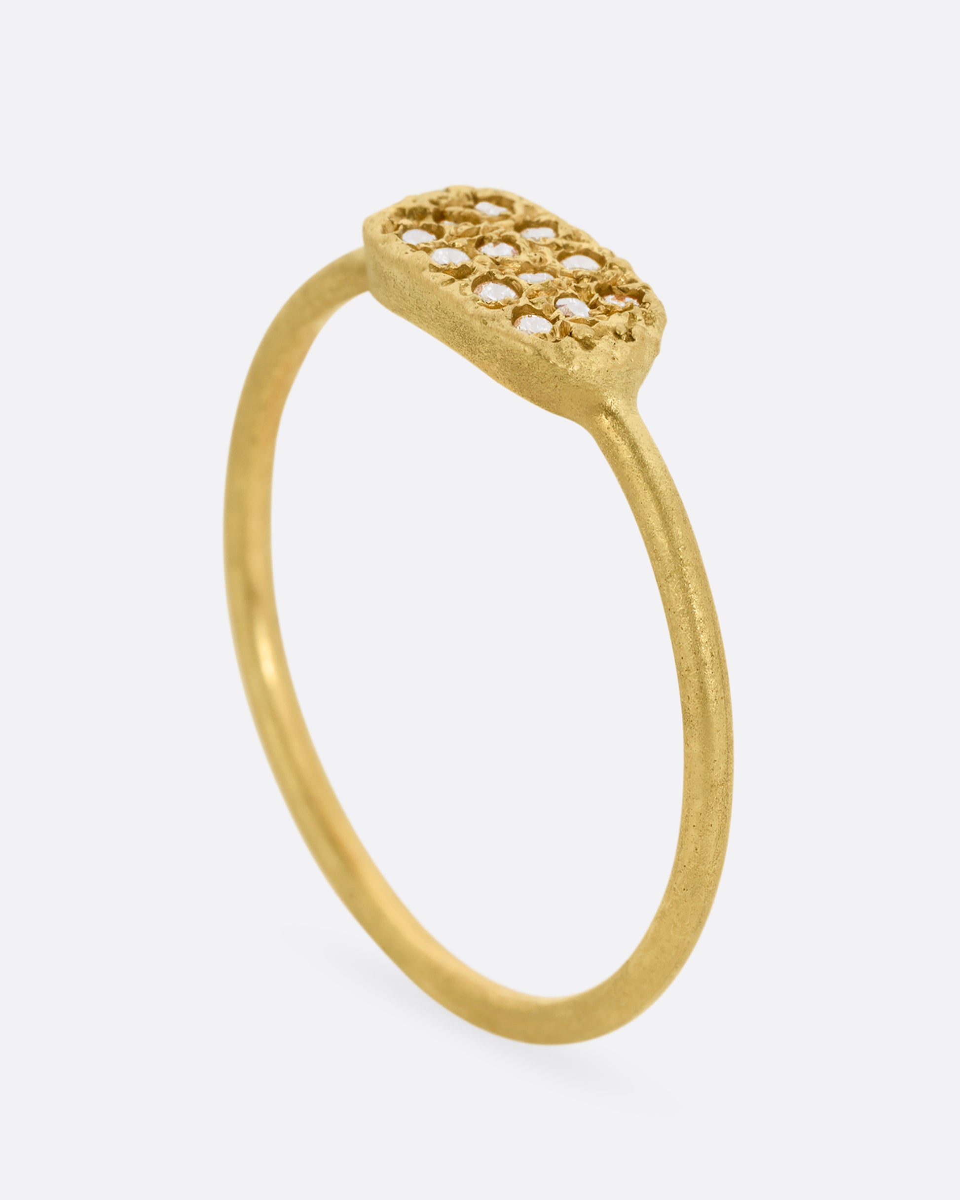 A yellow gold ring with a textured oval face with twelve white diamonds, shown standing up from the side.