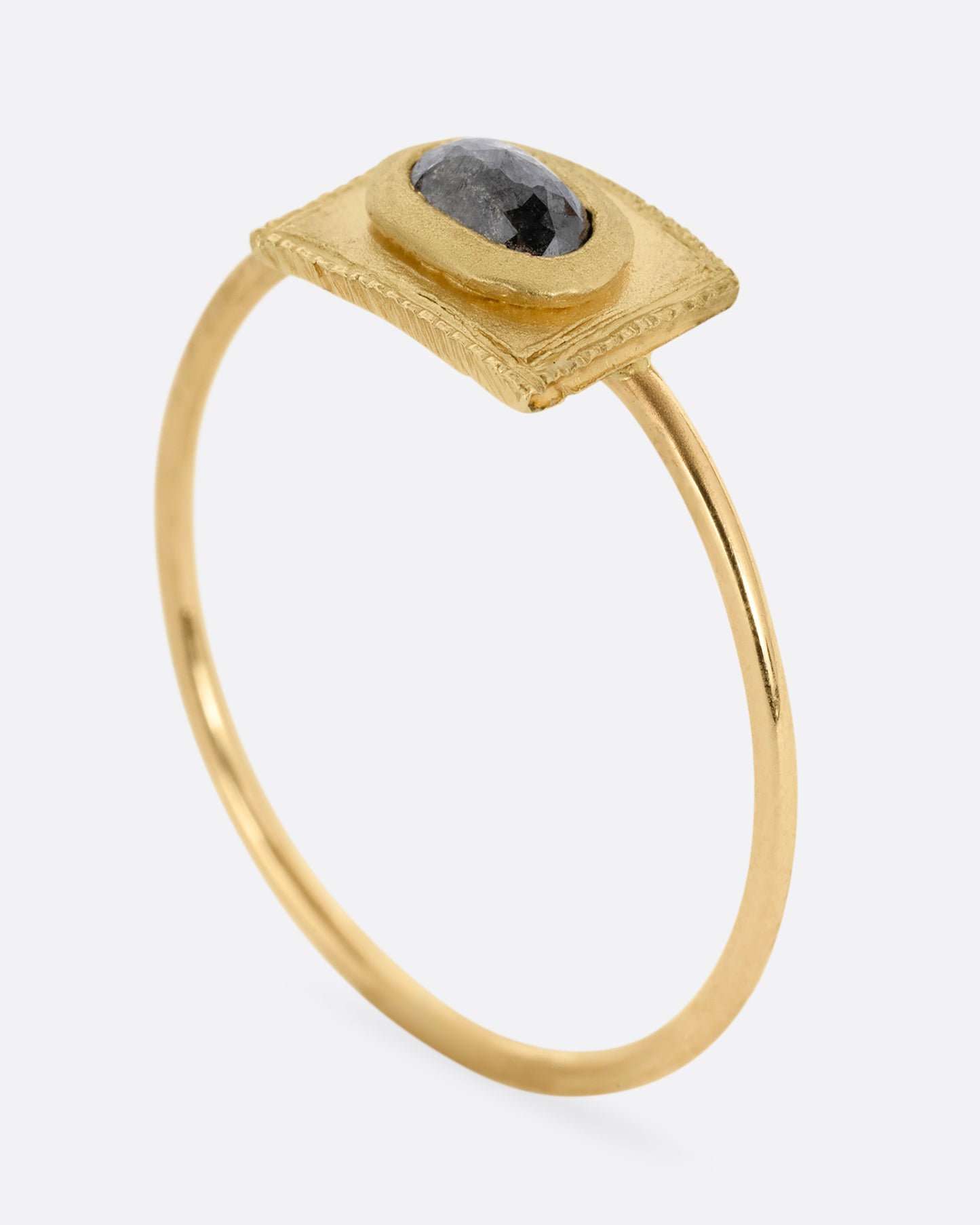 A yellow gold ring with a rectangular face and a rose cut diamond. Shown standing up from the side.