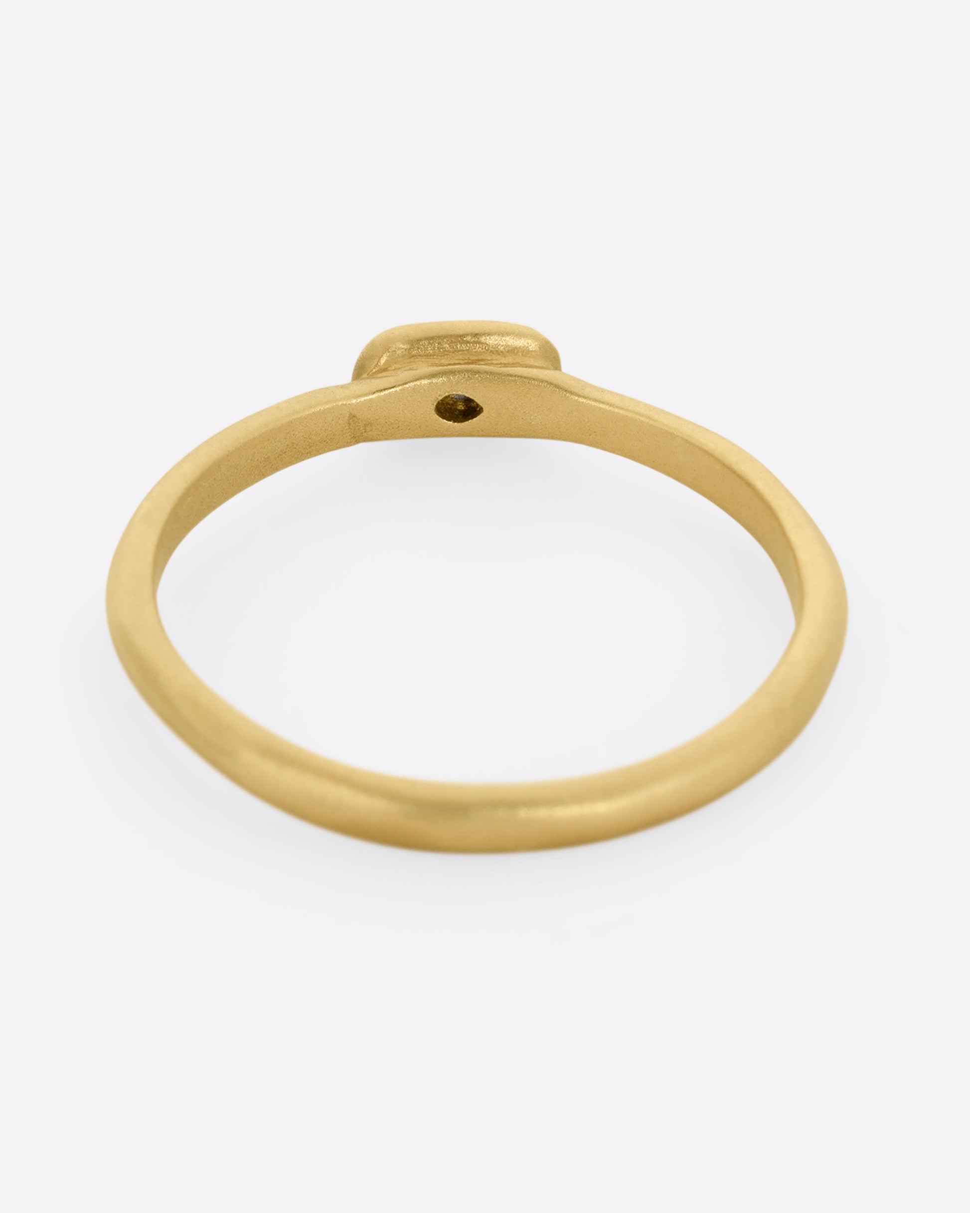 A yellow gold ring with a horizontally set salt and pepper baguette diamond, shown from the back.