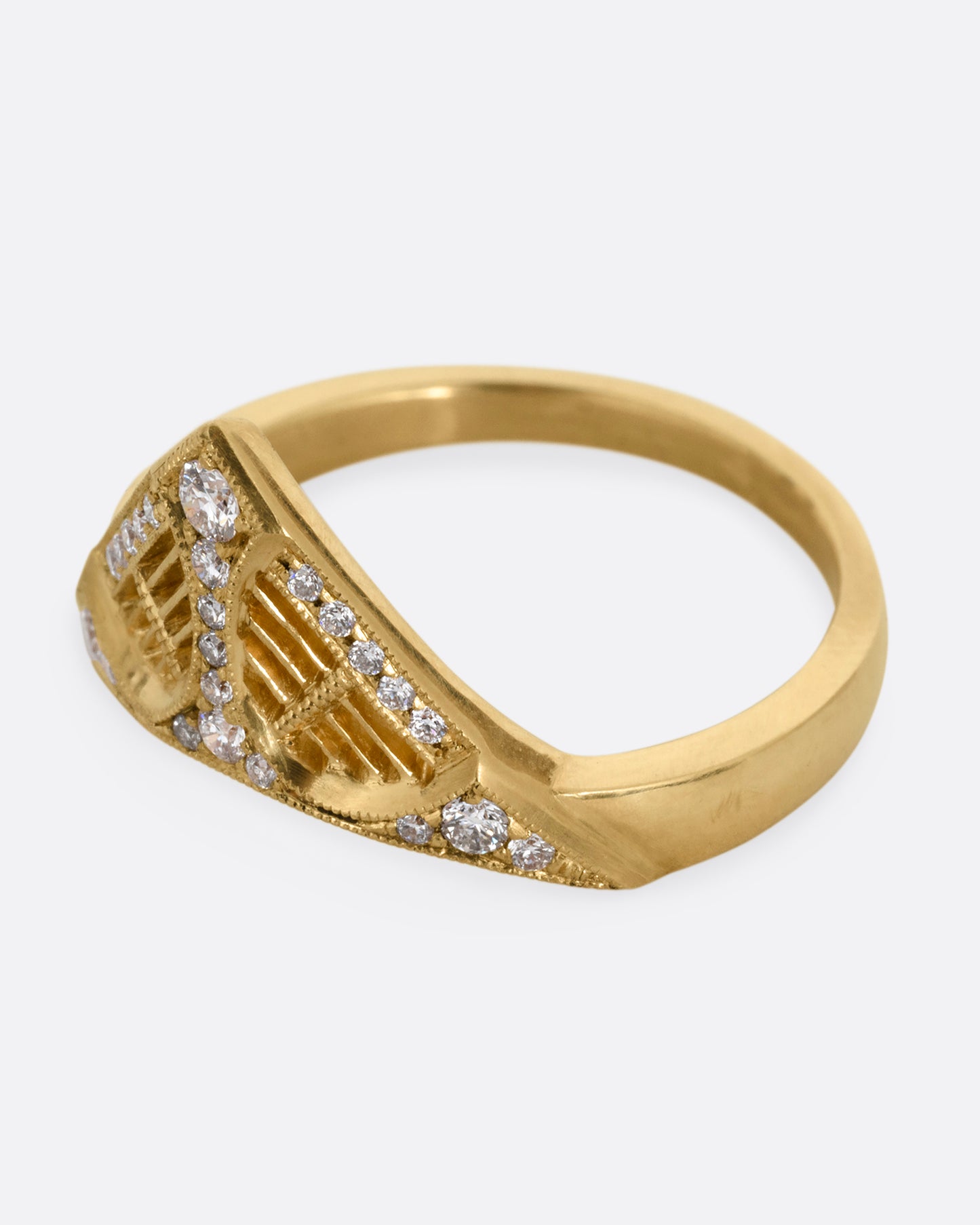 A yellow gold ring with a triangular face, white diamond accents, and cutouts. Shown from the side.