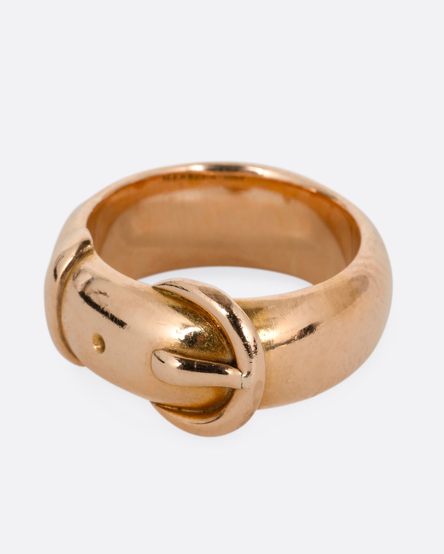 A yellow gold belt buckle ring with a curved edge. Shown from the side.