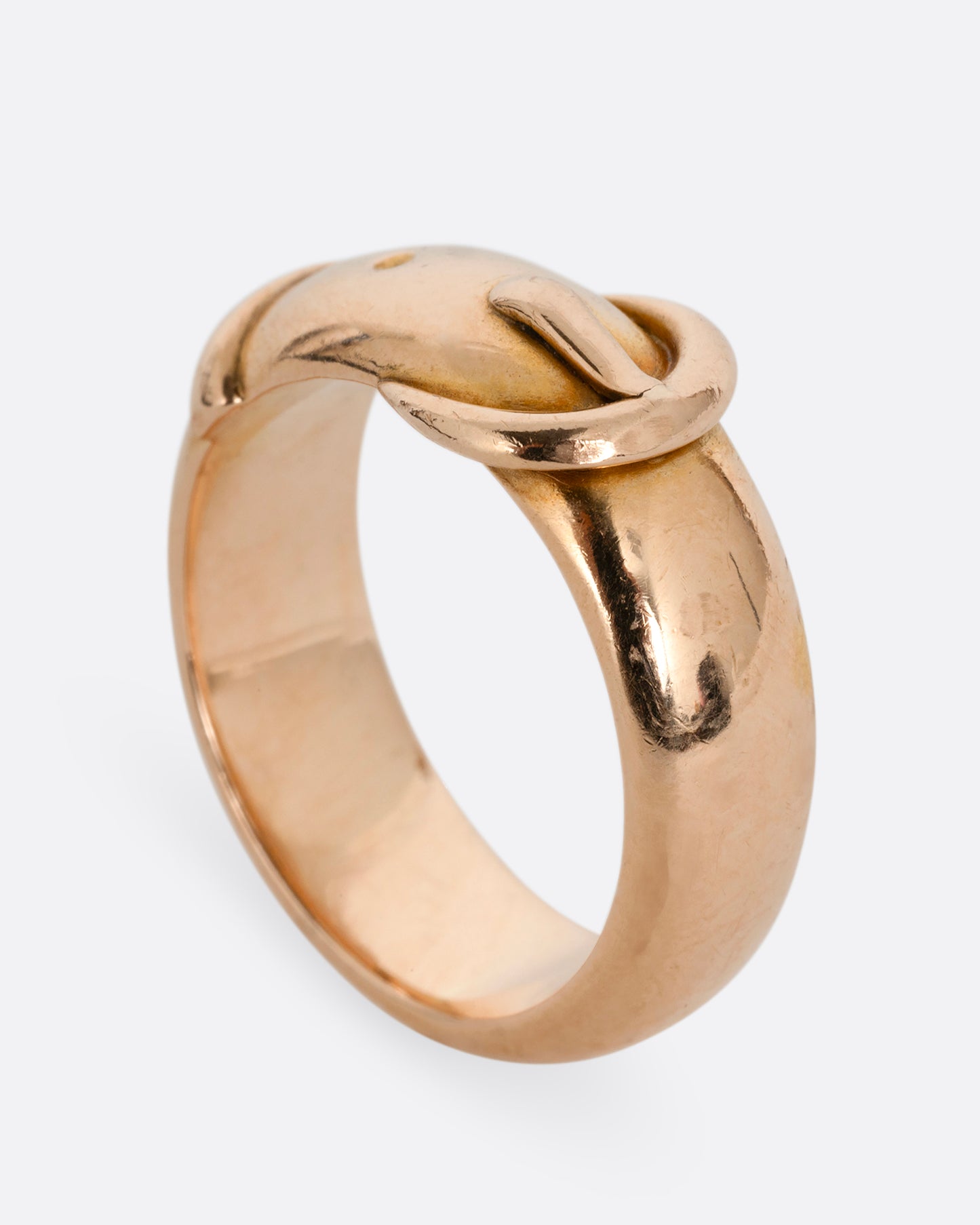 A yellow gold belt buckle ring with a curved edge. Shown standing up from the side.
