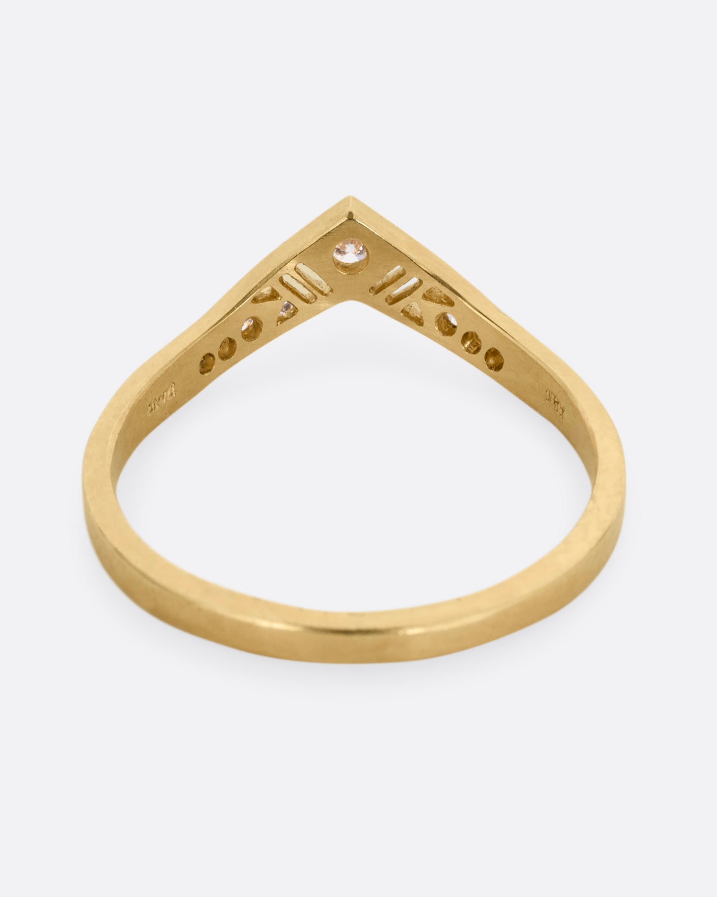 A slightly pointed yellow gold ring with diamonds and cutouts shown from the from the back.