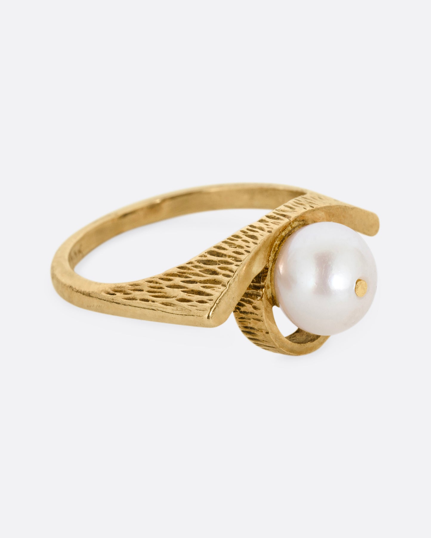 A yellow gold ring with a white pearl shown from the side.