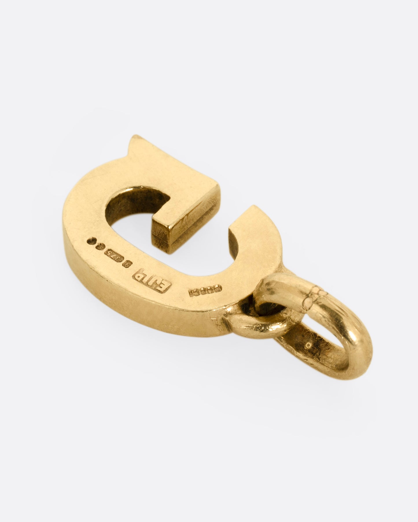 A yellow gold letter 'G' pendant shown from the back.