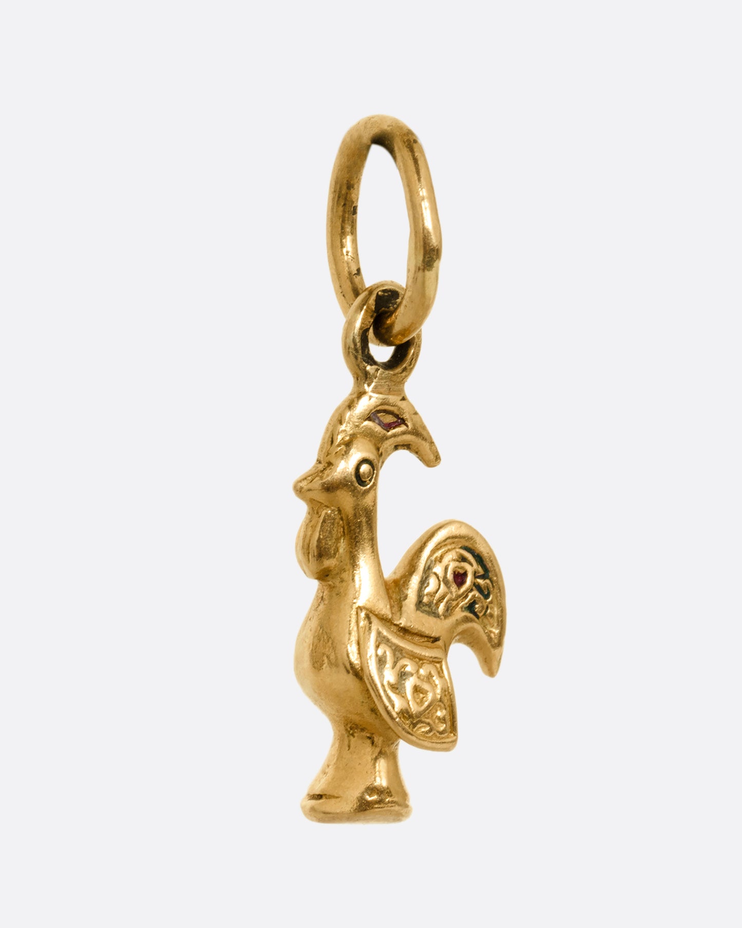 A yellow gold rooster charm shown from the side.