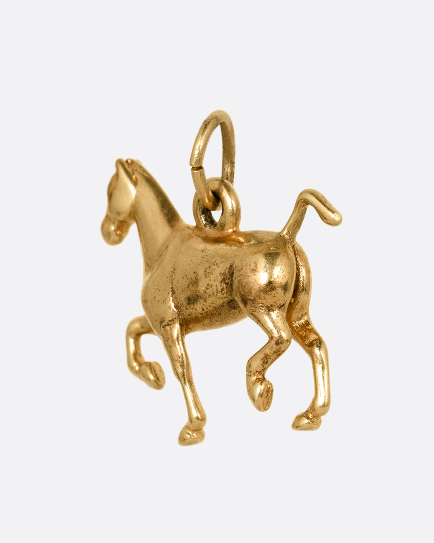 A yellow gold horse charm shown from the back.