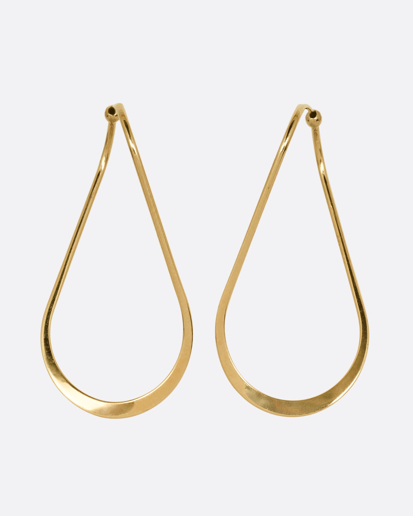 A pair of yellow gold hoop earrings with a subtle twist at the top. Shown from the back.