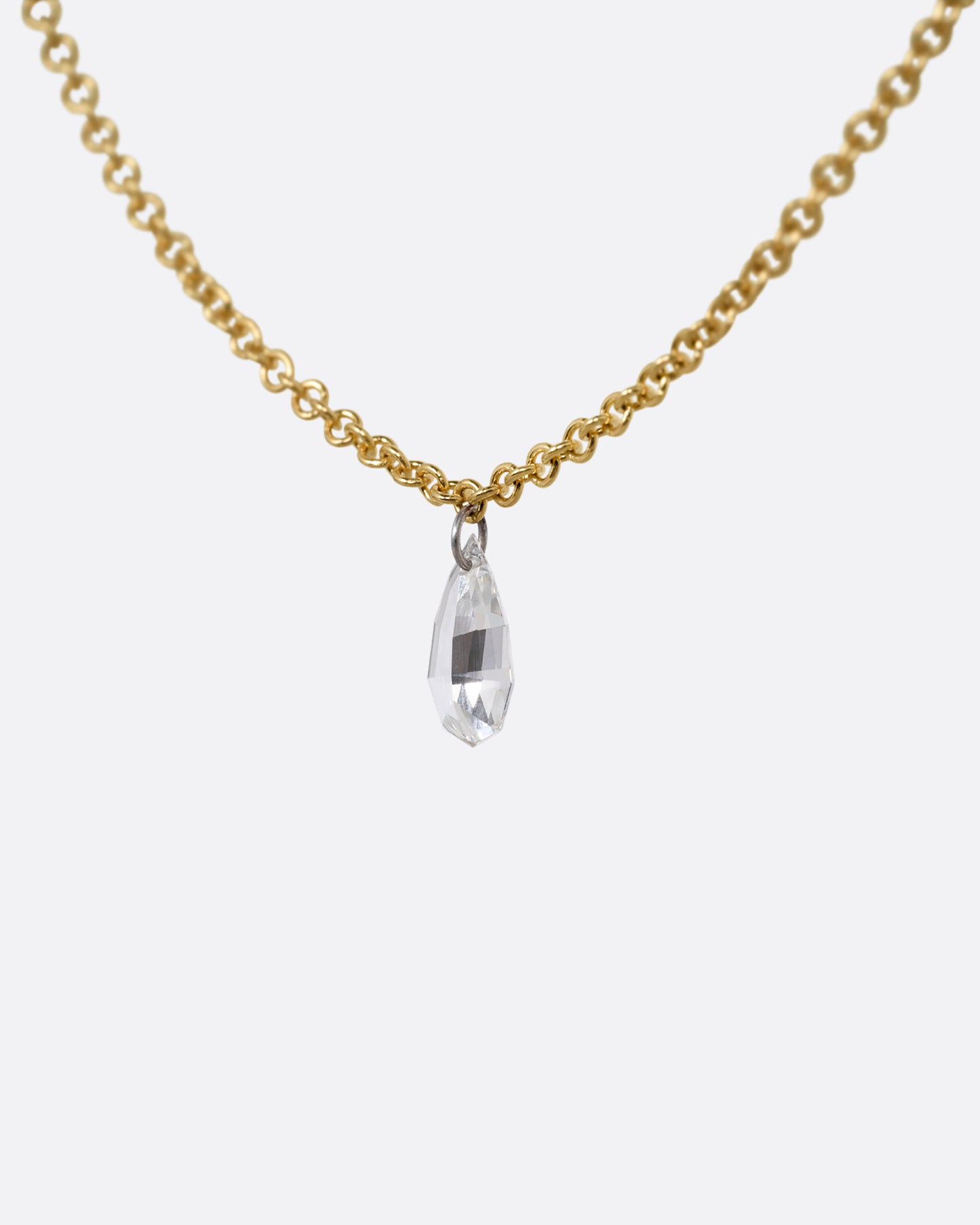 A yellow gold cable chain necklace with a pear shaped diamond. Shown from the side.