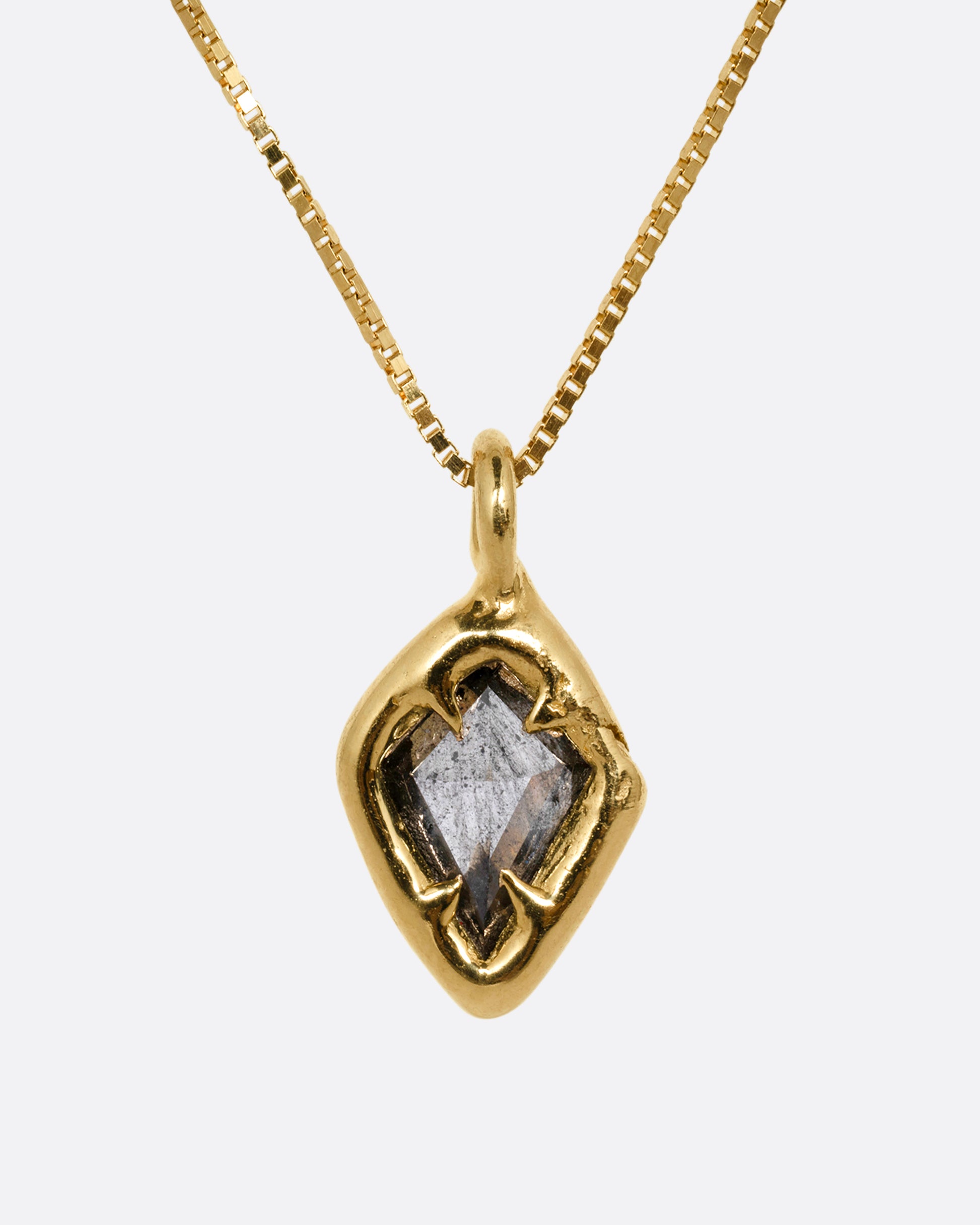 A yellow gold necklace with a kite shaped salt and pepper diamond in a claw setting. Shown from the front.