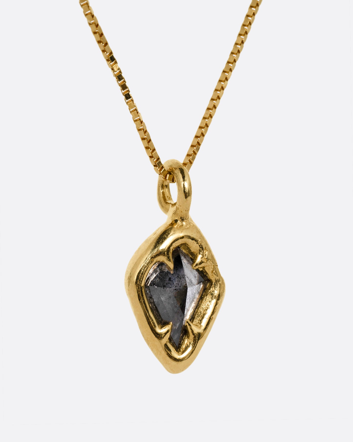 A yellow gold necklace with a kite shaped salt and pepper diamond in a claw setting. Shown from the side.