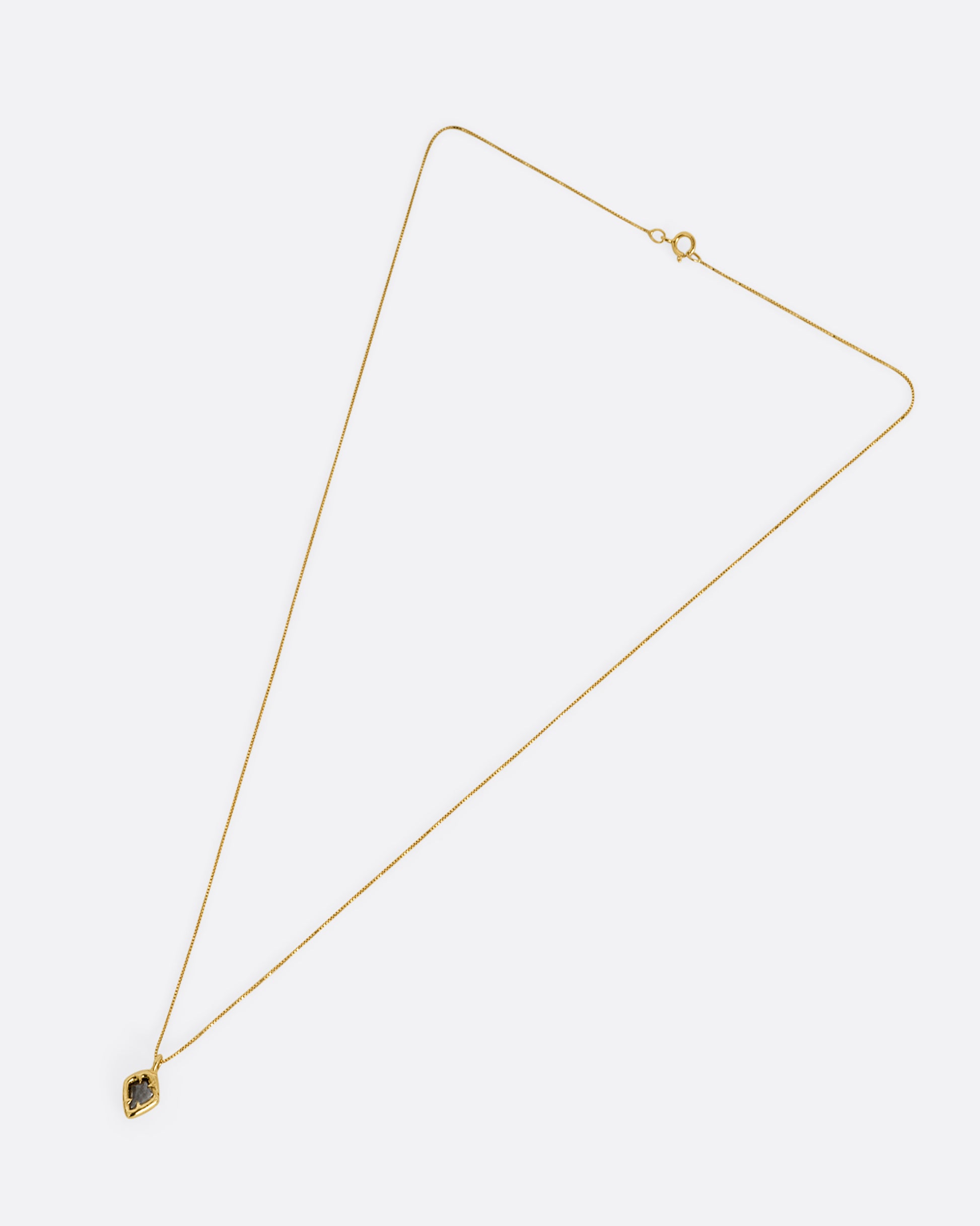 A yellow gold necklace with a kite shaped salt and pepper diamond in a claw setting. Shown from the front.
