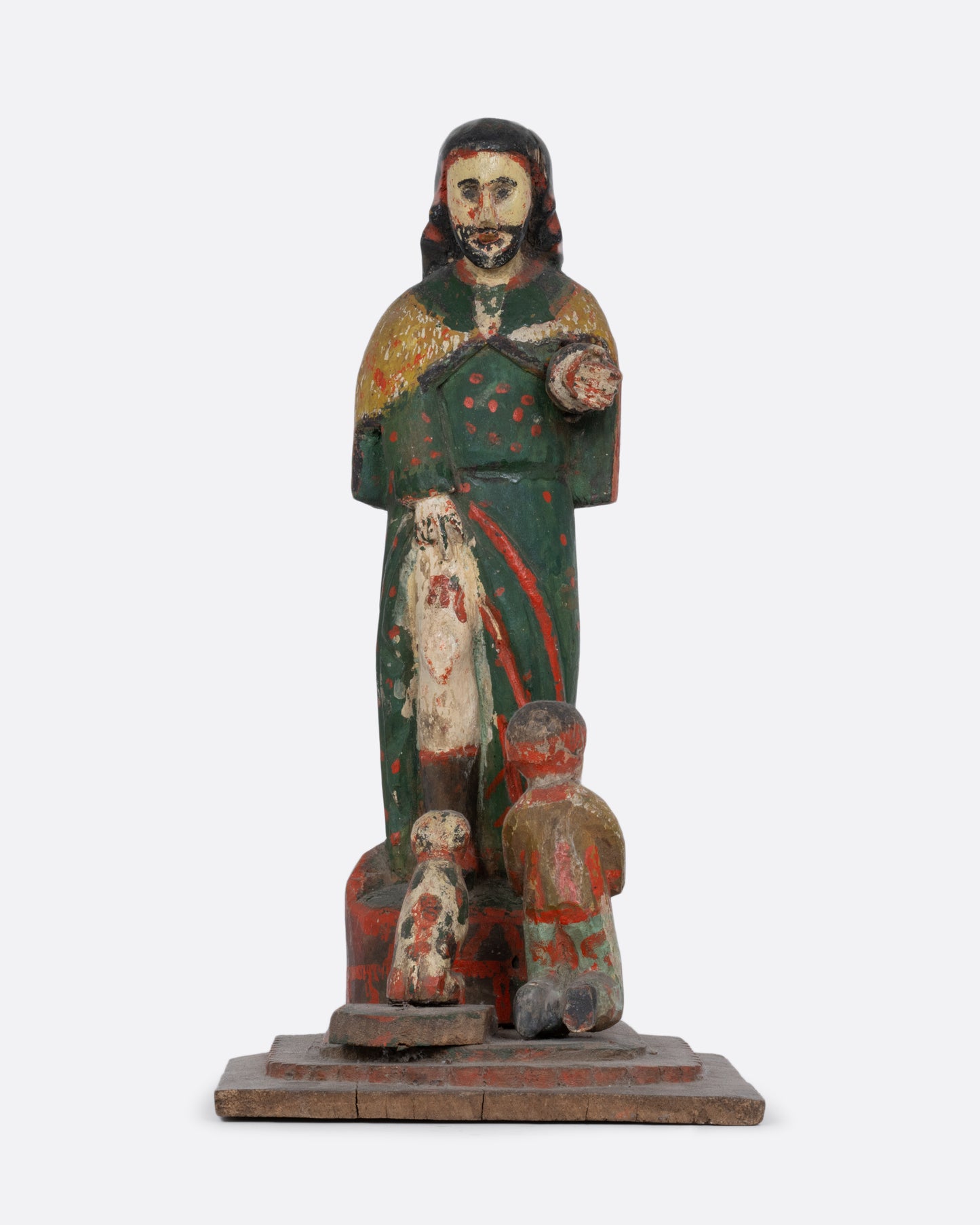 A wooden hand carved and painted Saint statue with a child and dog at its feet. Shown from the front.