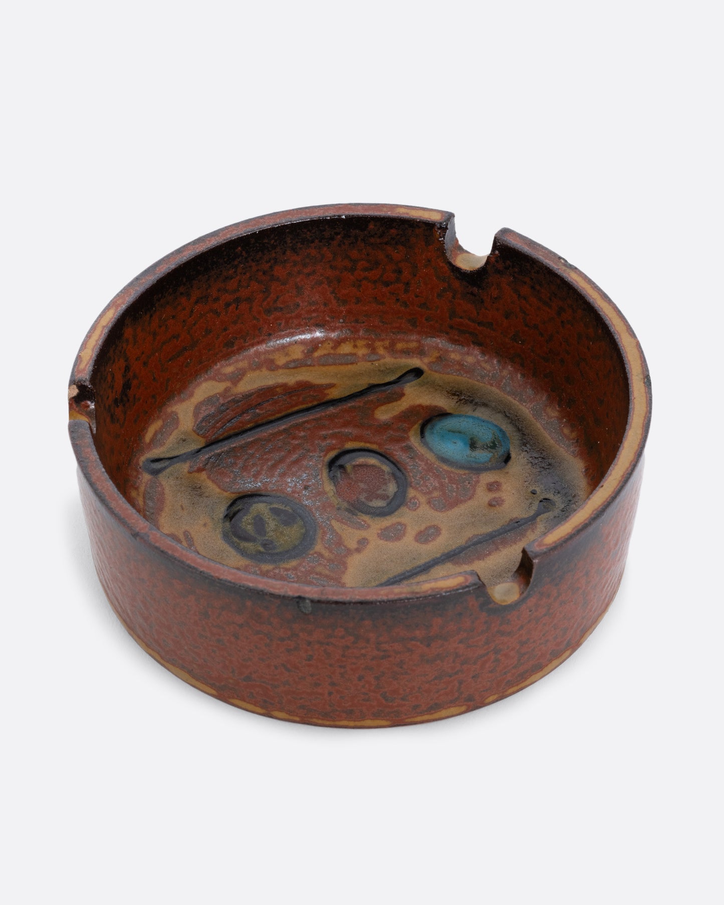 A hand painted ceramic ashtray with three cigarette grooves. Shown from the top.