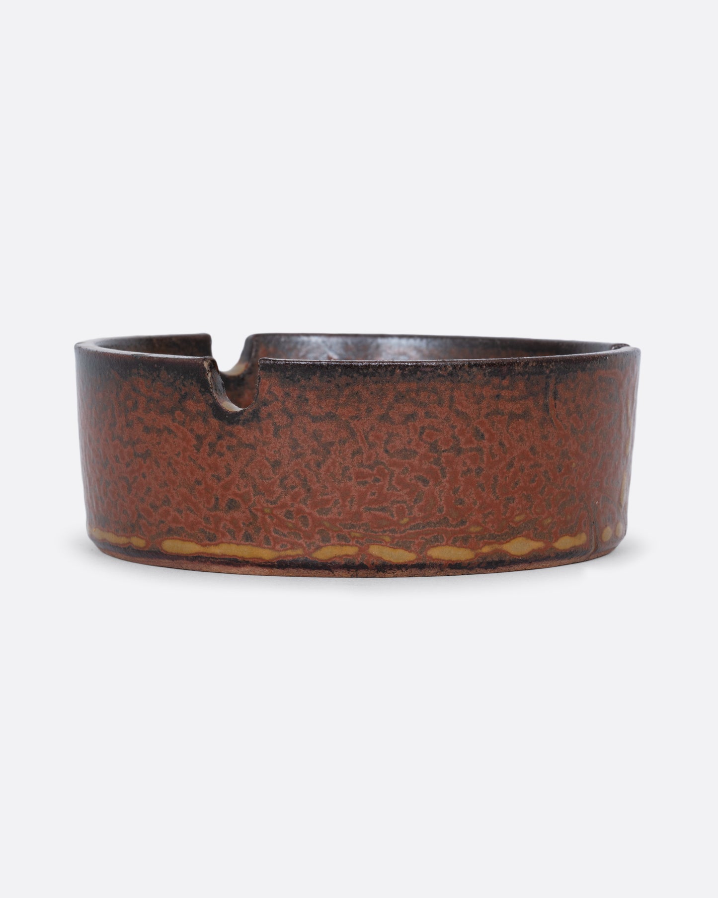 A hand painted ceramic ashtray with three cigarette grooves. Shown from the side.