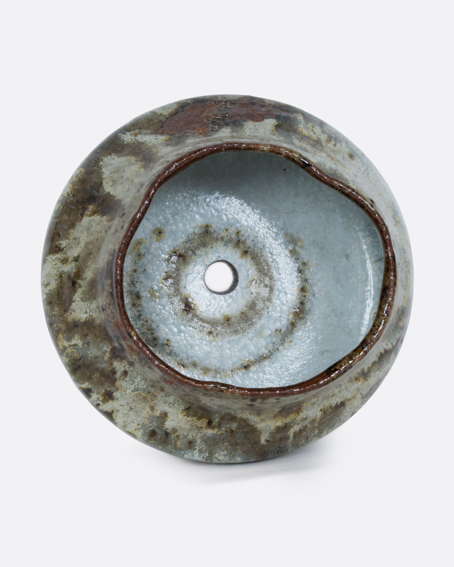 This ceramic planter with a green marbled glaze and drainage hole. Shown on its side from the top.