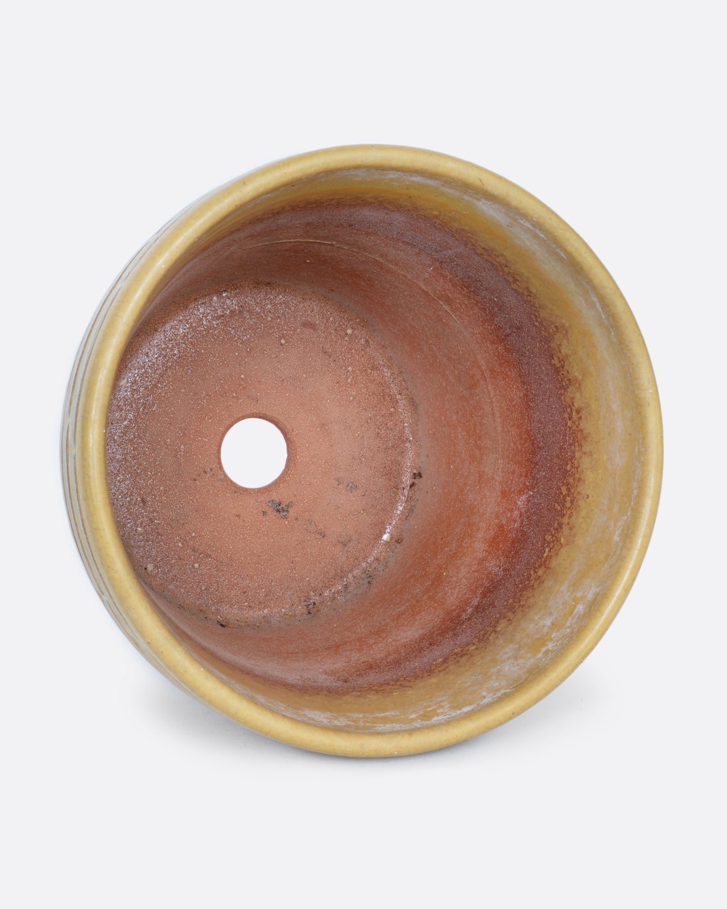 A terracotta planter with a textural stamped pattern and a drainage hole at its base. Shown lying flat from the top.