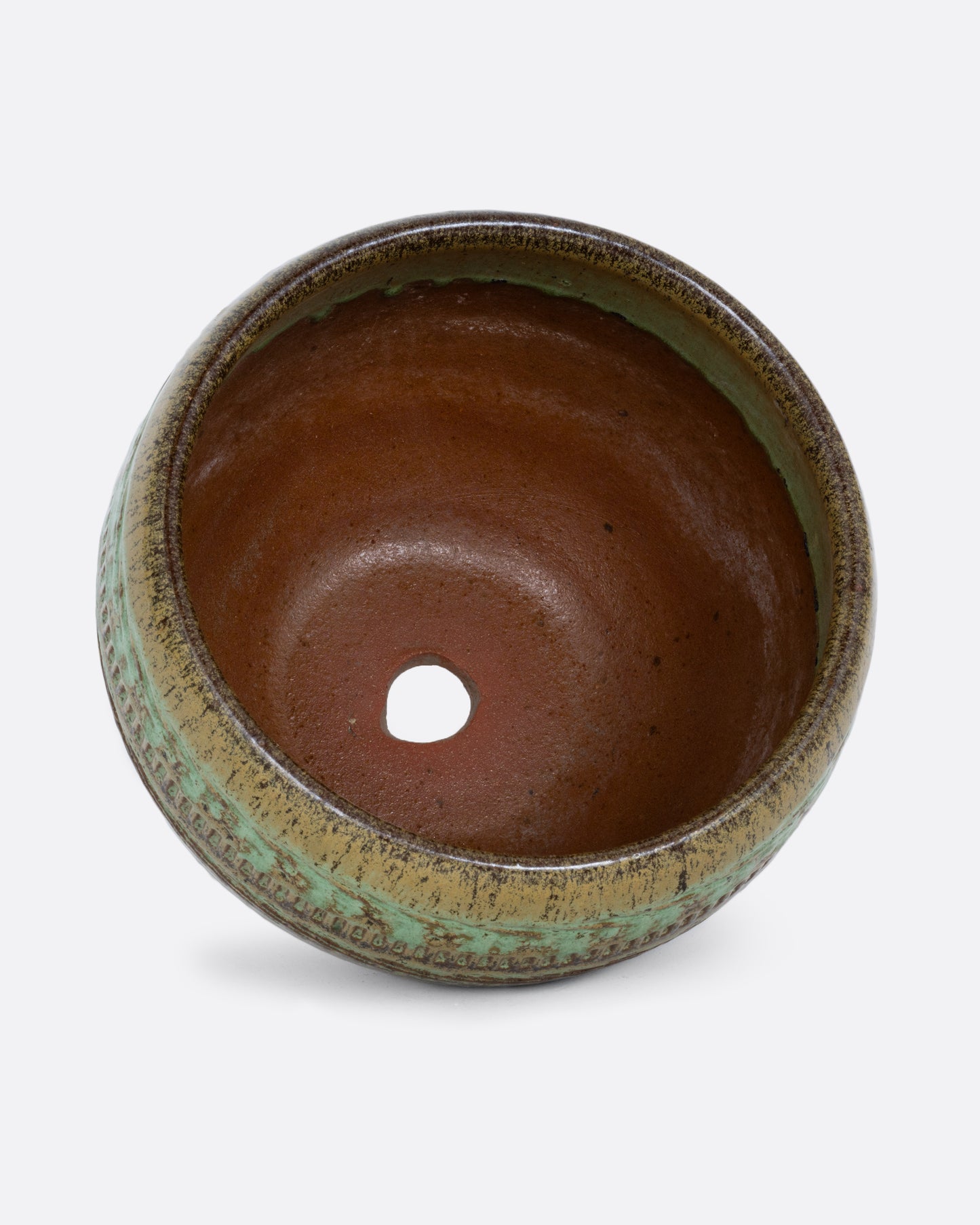 A round green textured pot with a hole in it base. Shown standing on its side from the top.