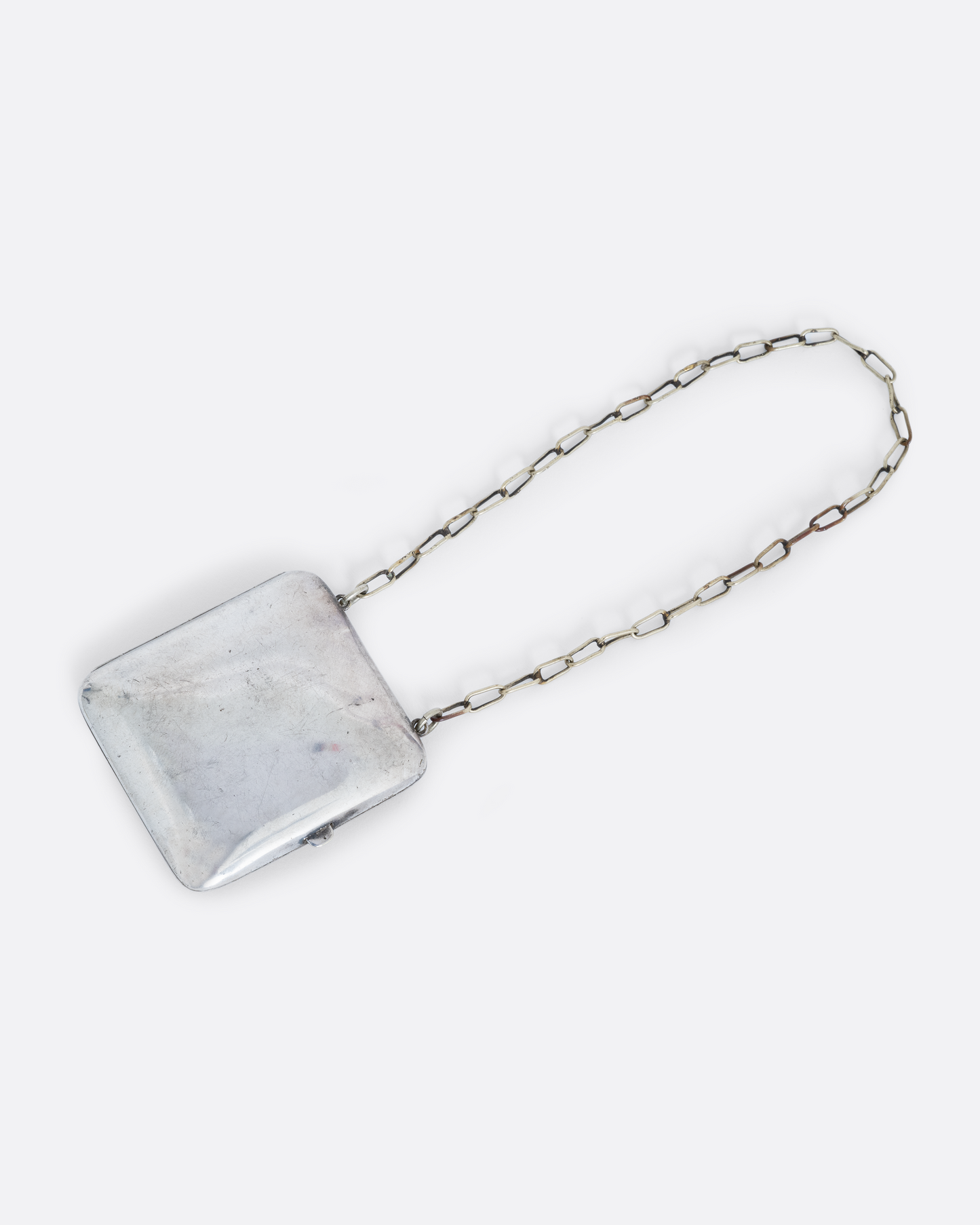 A silver square velvet lined coin purse with a cable wrist chain. Shown from the back.