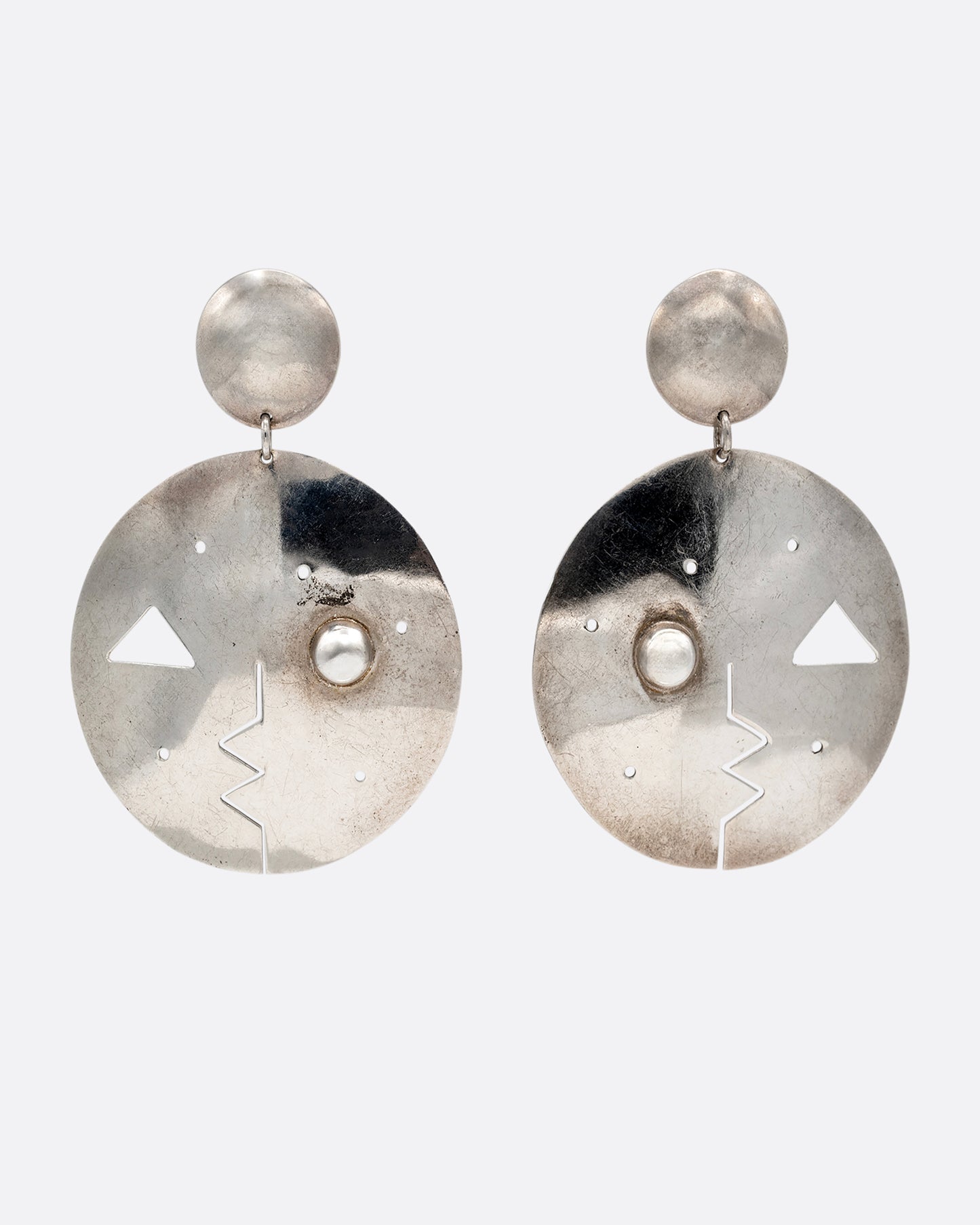 A pair of round drop stud earrings with geometric cutout faces. Shown from the front.
