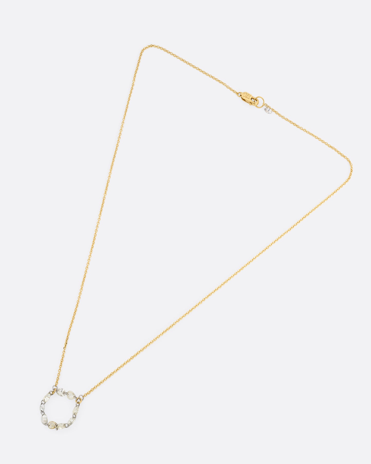 A yellow gold cable chain necklace with a loop of nine rose cut diamonds at the center. Shown from the front.