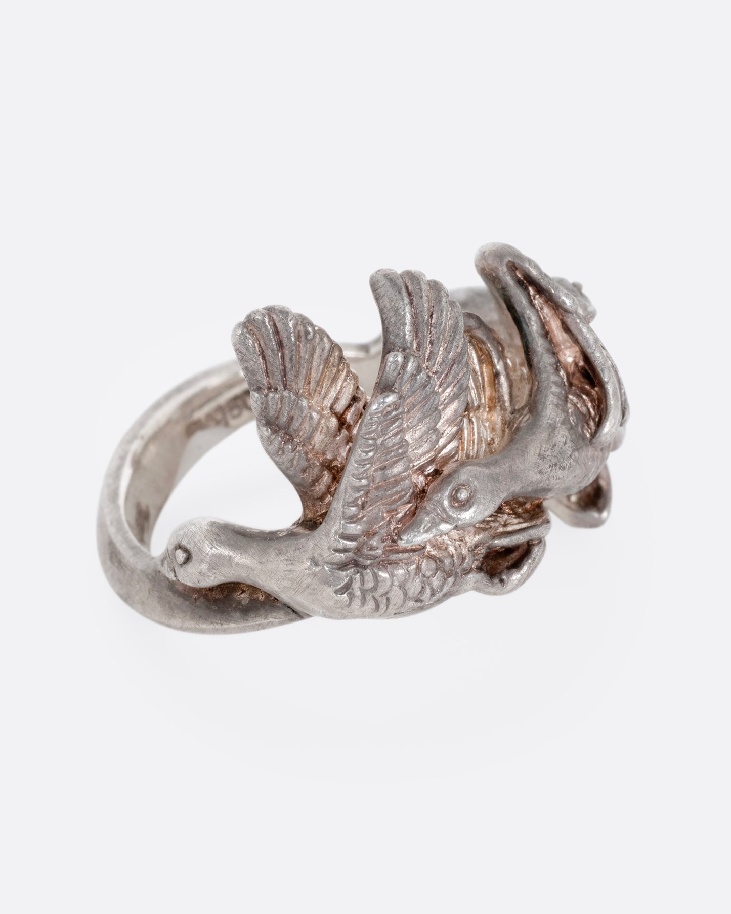A silver ring with a flock of geese flying along the face. Shown from the side.