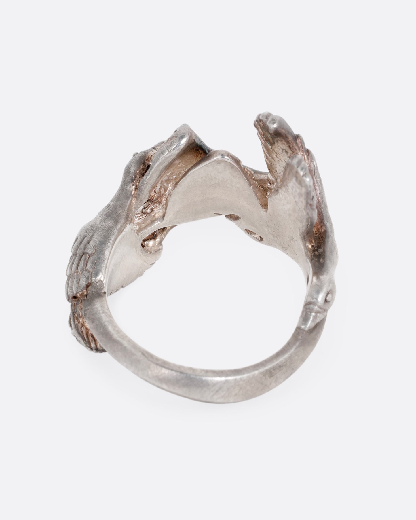 A silver ring with a flock of geese flying along the face. Shown from the back.