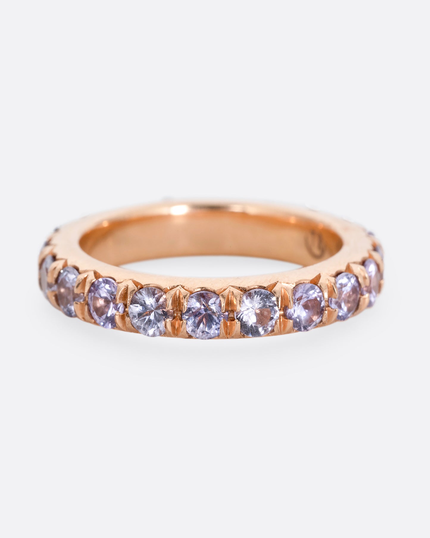 A rose gold eternity ring with lavender sapphires. Shown from the front.