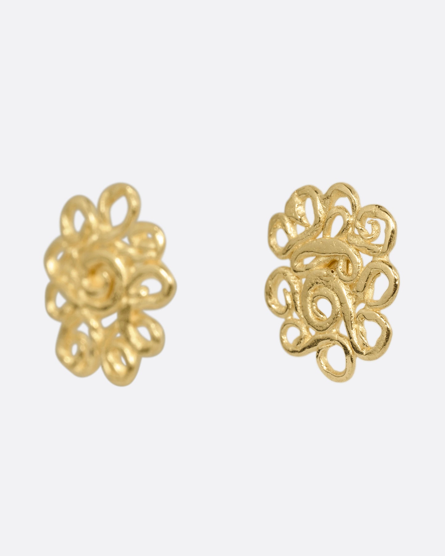 A pair of yellow gold stud earrings with swirling vines in a lacy pattern. Shown from the side.