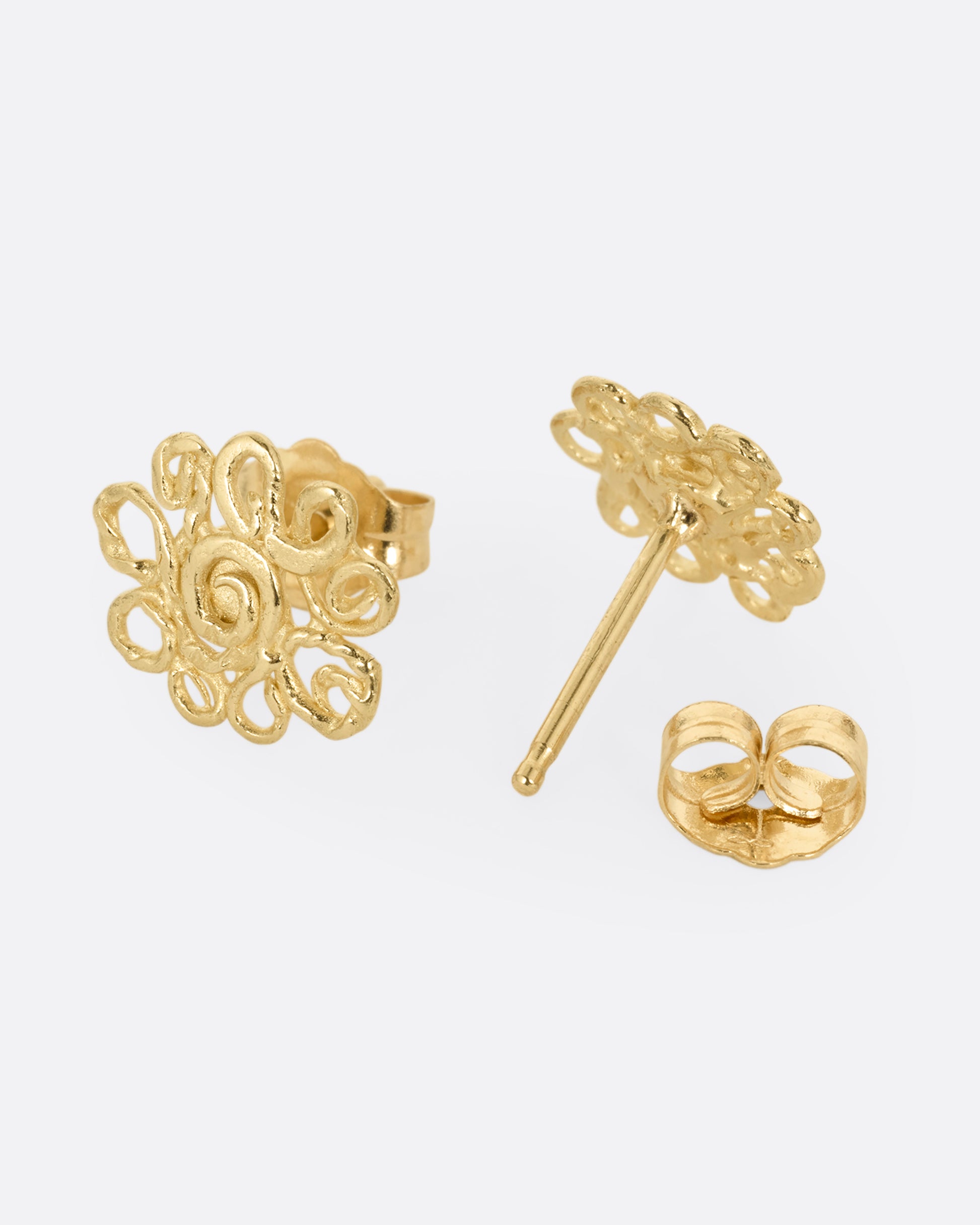 A pair of yellow gold stud earrings with swirling vines in a lacy pattern. One earring is shown from the front, the other open from the back.