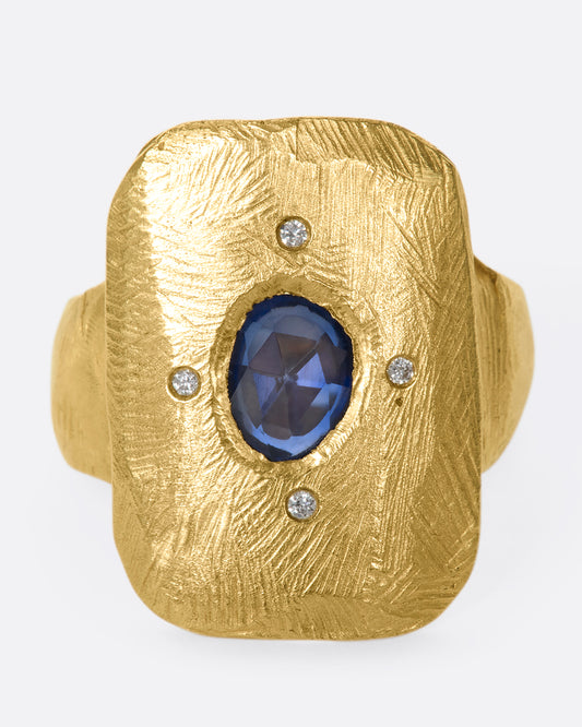 An 18k gold hand carved cocktail ring with a rose-cut, dark blue sapphire dotted with four star-like diamonds