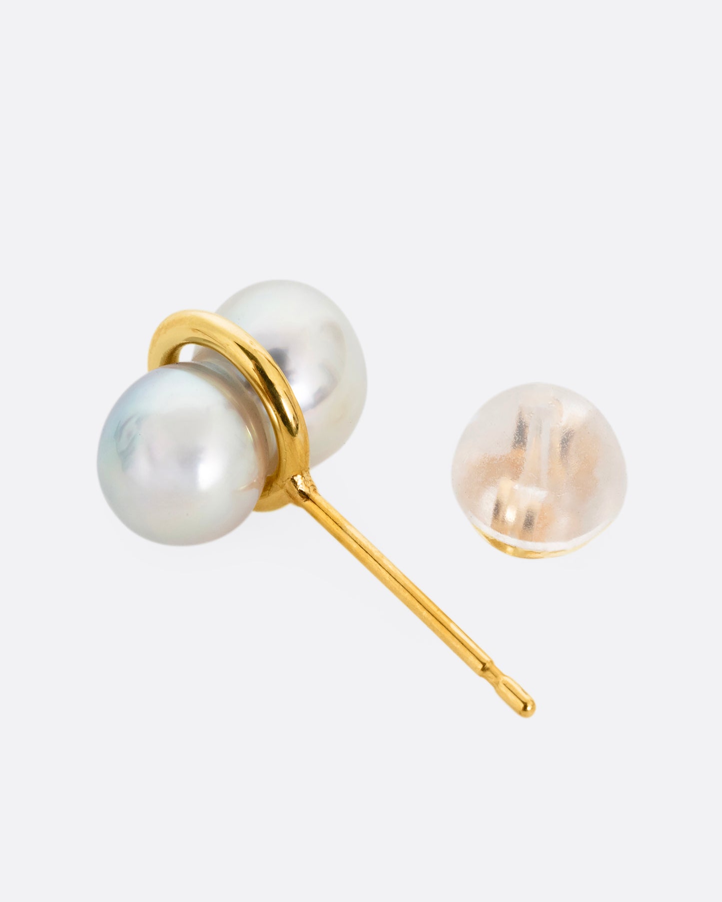 A pearl earring with a gold loop around the middle, shown from the side.