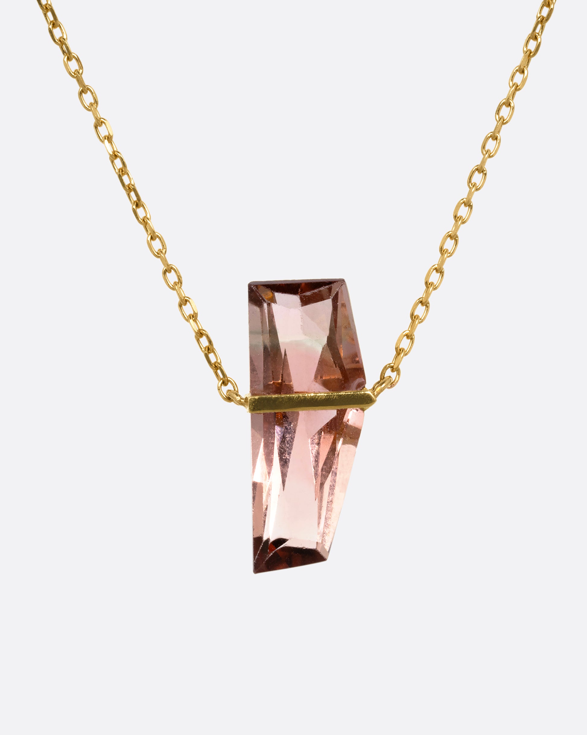 A yellow gold cable chain necklace with a five sided rosy quartz in an open bar setting. Shown from the front.
